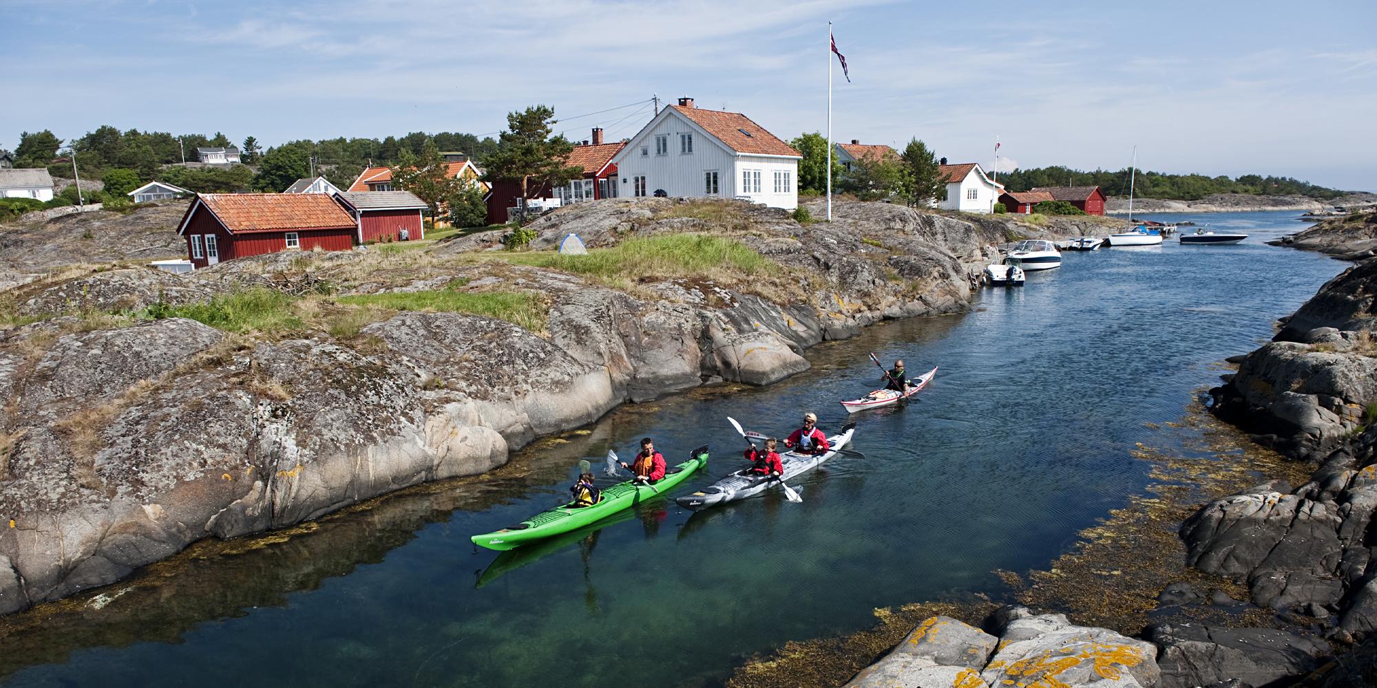 A family kayaking through a strait in the archipelago of Risør, Southern Norway