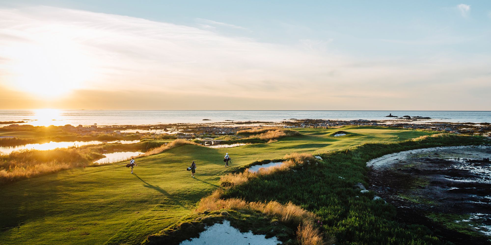 Three people playing golf under the midnight sun at Lofoten Links