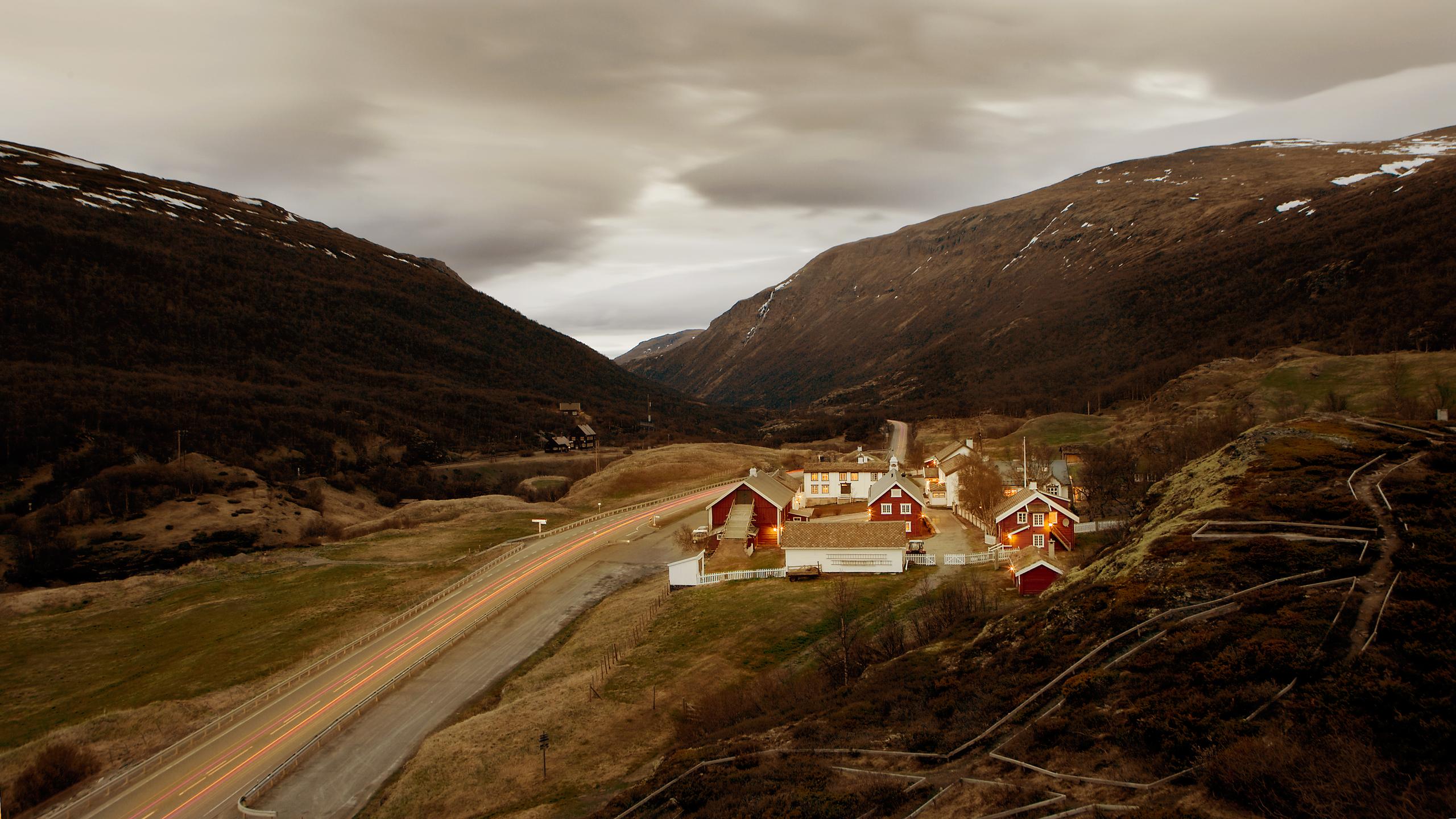 Kongsvold Fjellstue in Dovrefjell. It is surrounded by mountains and with a road going past on the left.