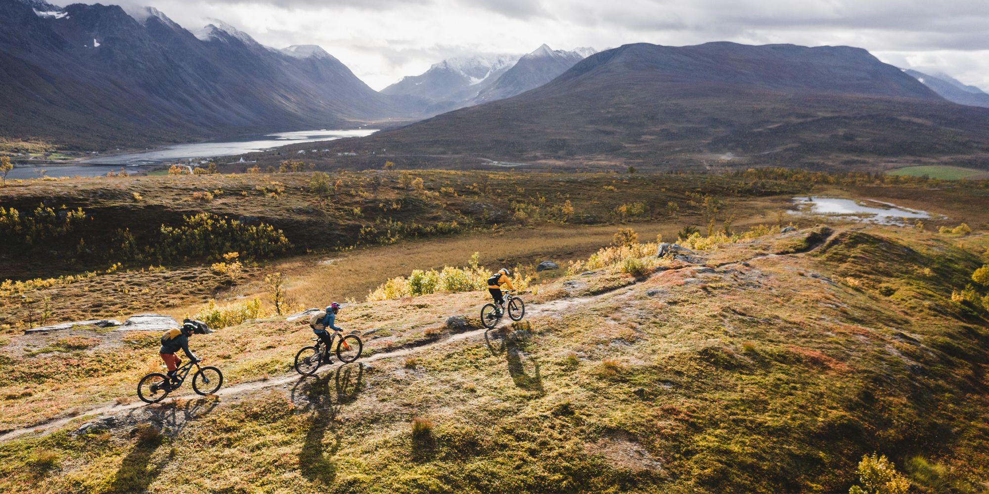 Three people mountain biking in the Lyngenfjord region in Northern Norway, in the mountains