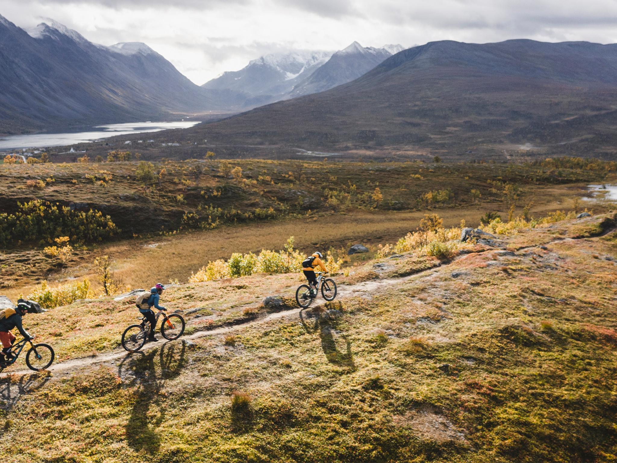 Three people mountain biking in the Lyngenfjord region in Northern Norway, in the mountains