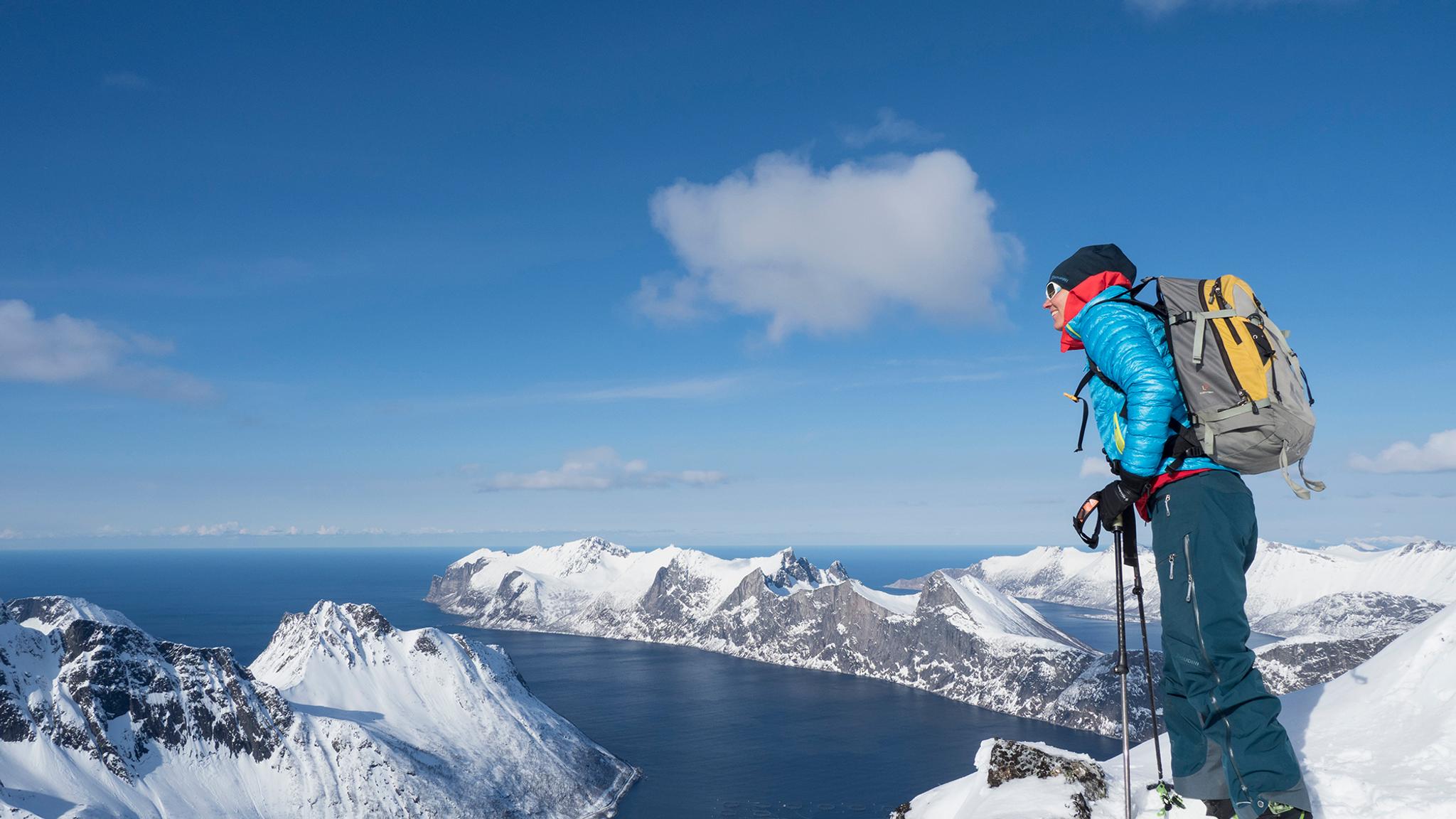A woman standing at the top of a mountain in Senja in Northern Norway during winter