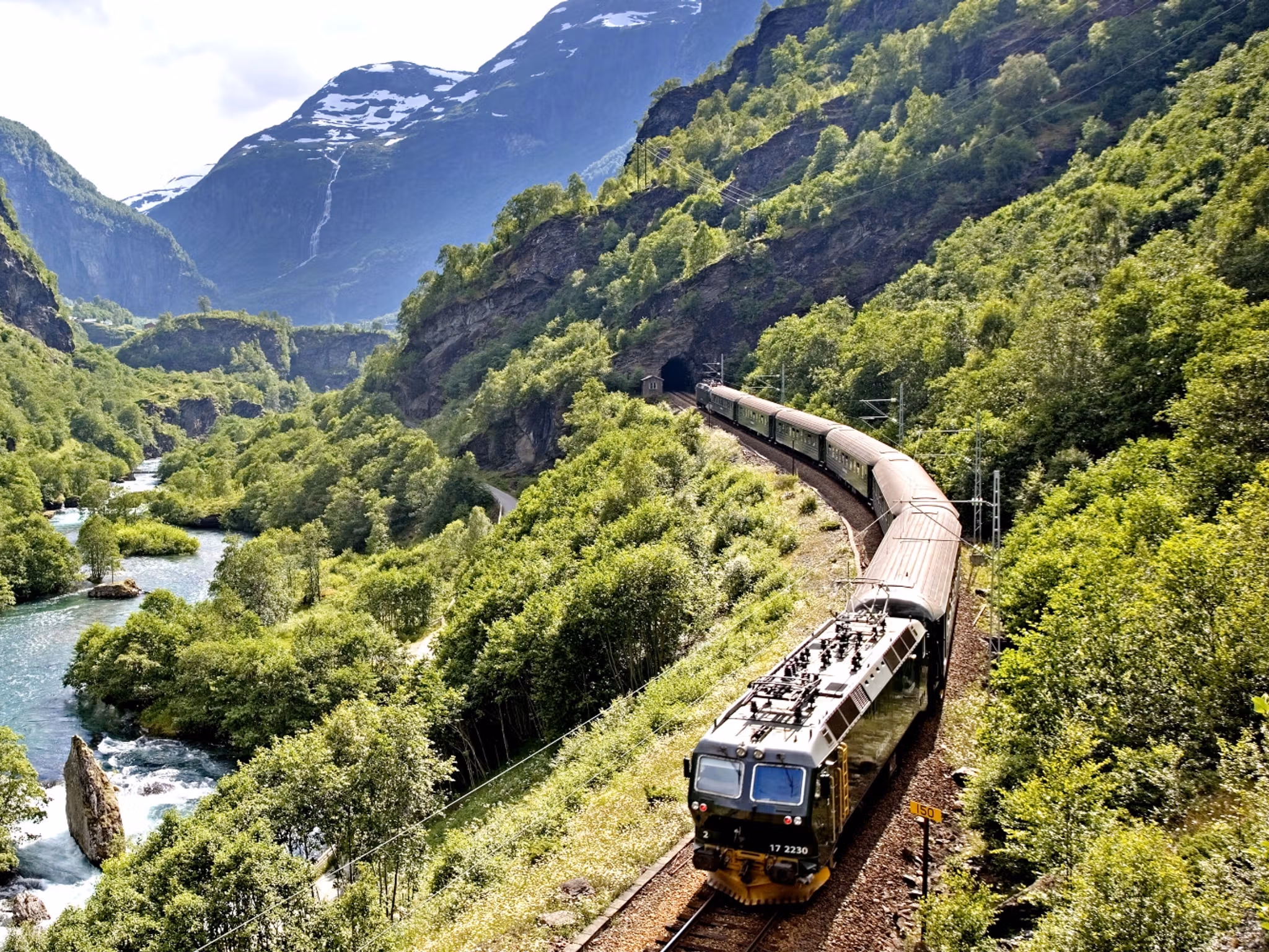 The Flåm Railway going through the landscape of green hills and spectacular mountains in Fjord Norway