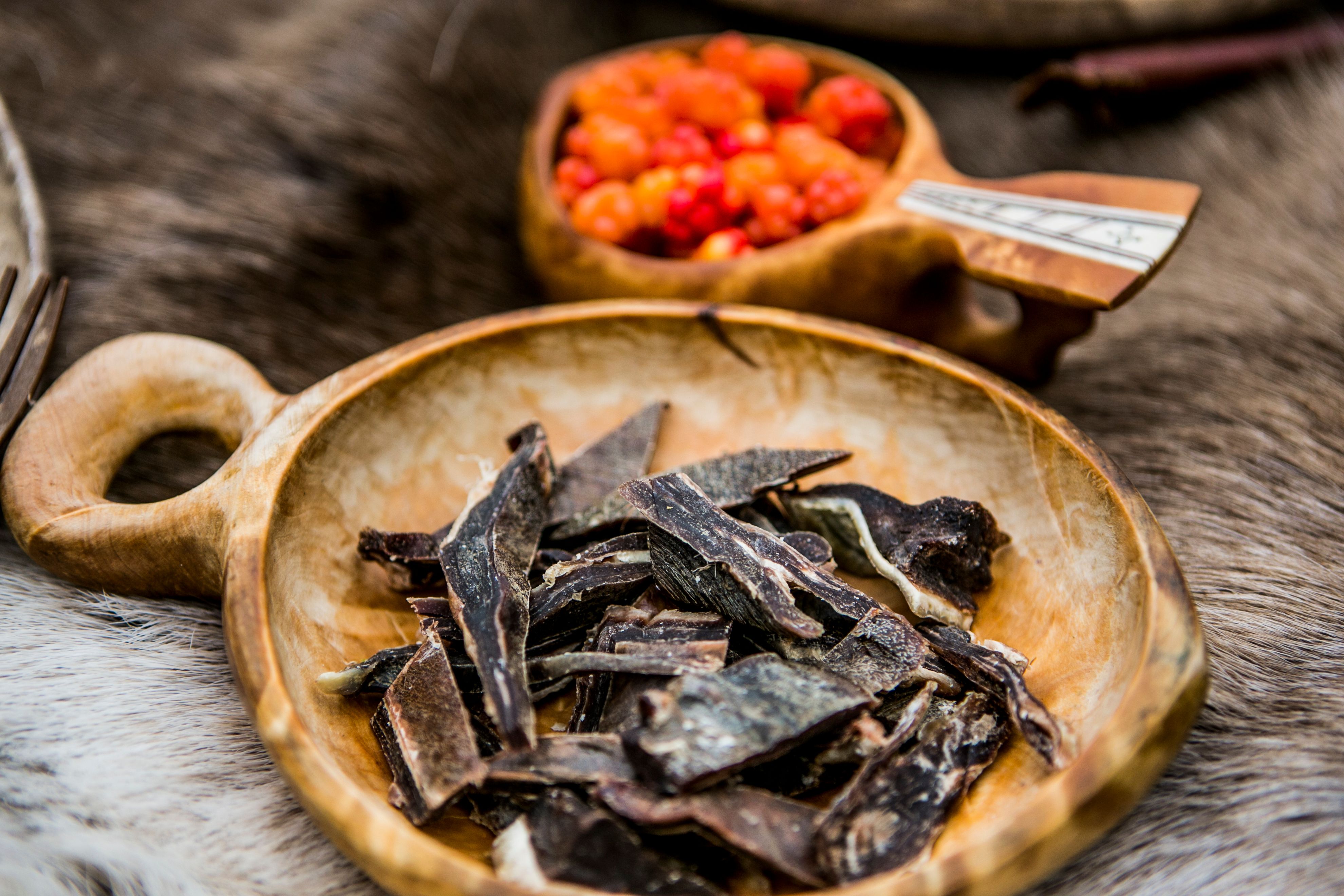 Curend reindeer meat on a plate and cloudberries in a bowl in Finnmark, Northern Norway