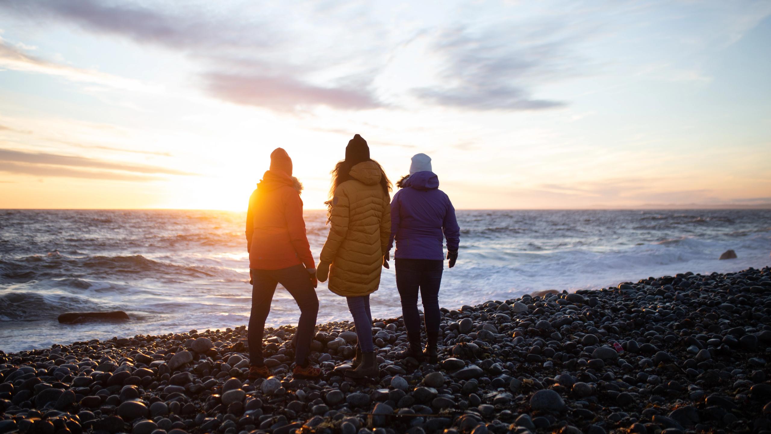 Tre damer går på stranden i Mølen i Larvik