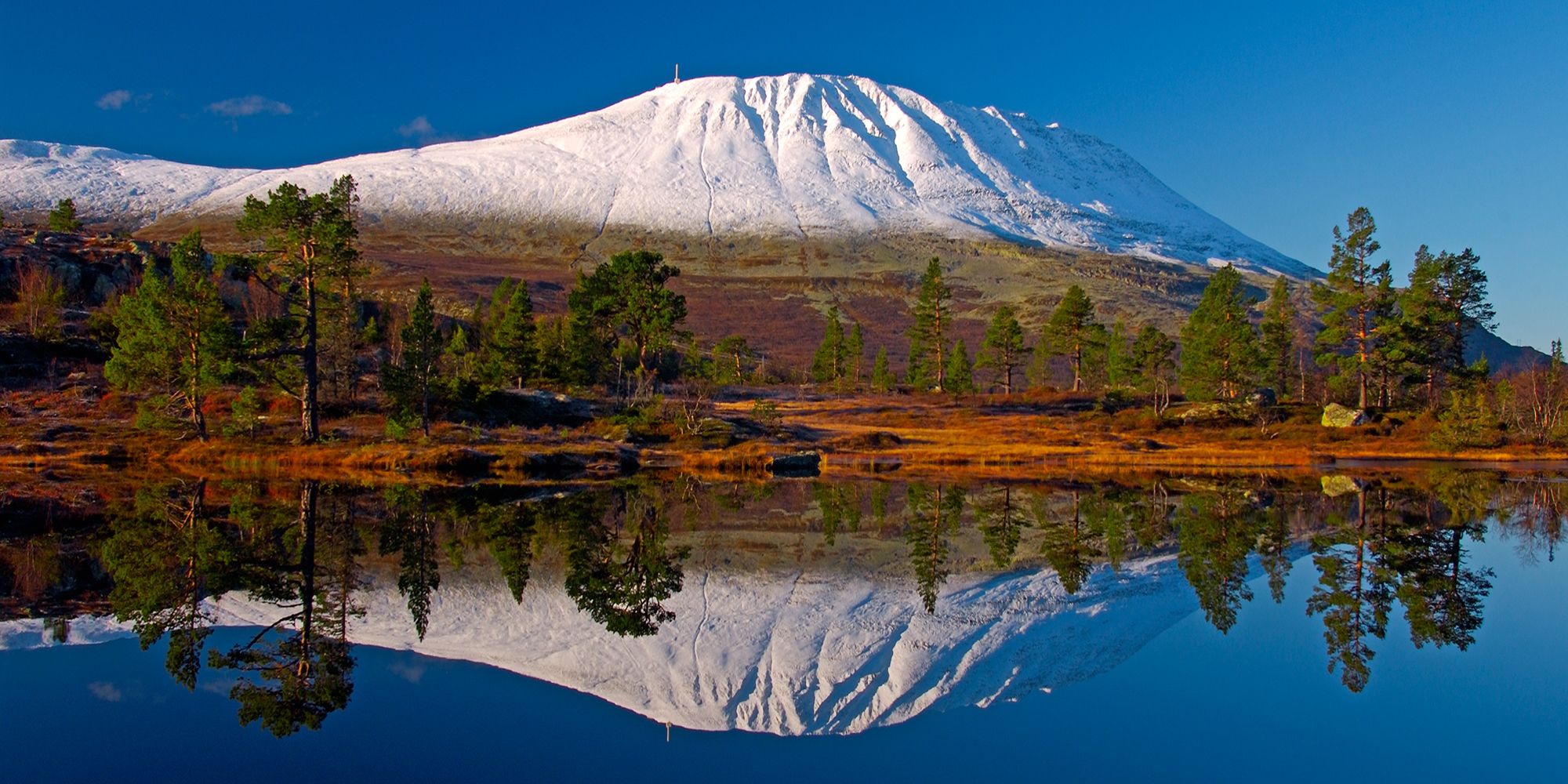 A snowclad Mount Gaustatoppen reflected in a lake. Telemark, Norway