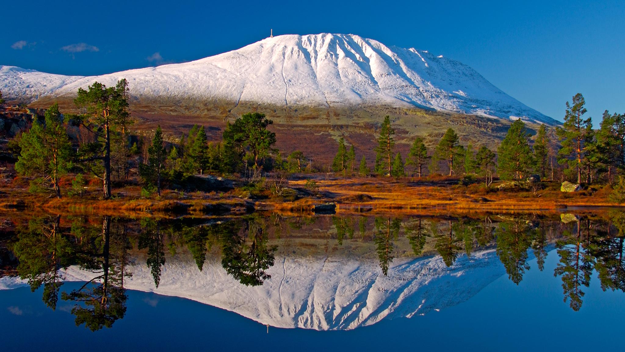 A snowclad Mount Gaustatoppen reflected in a lake. Telemark, Norway