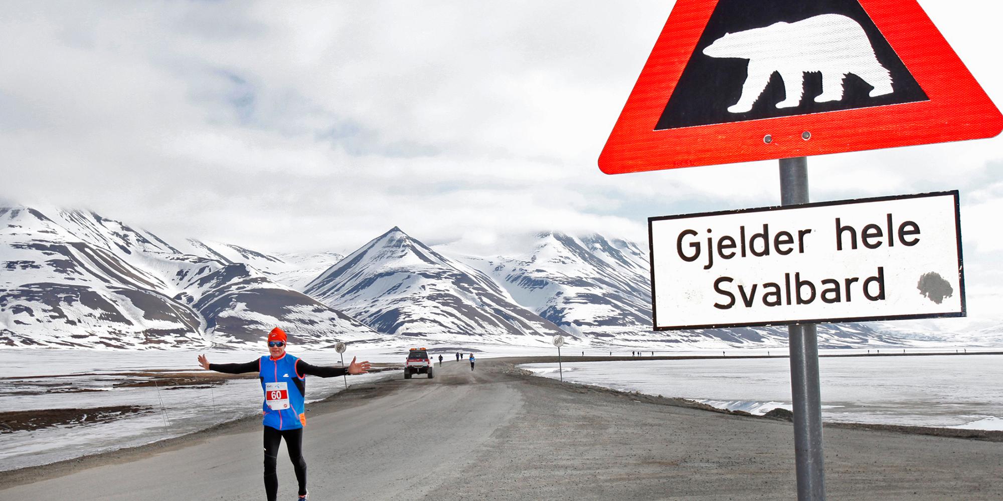 En maratonløper passerer et isbjørnskilt på Spitsbergen, Svalbard