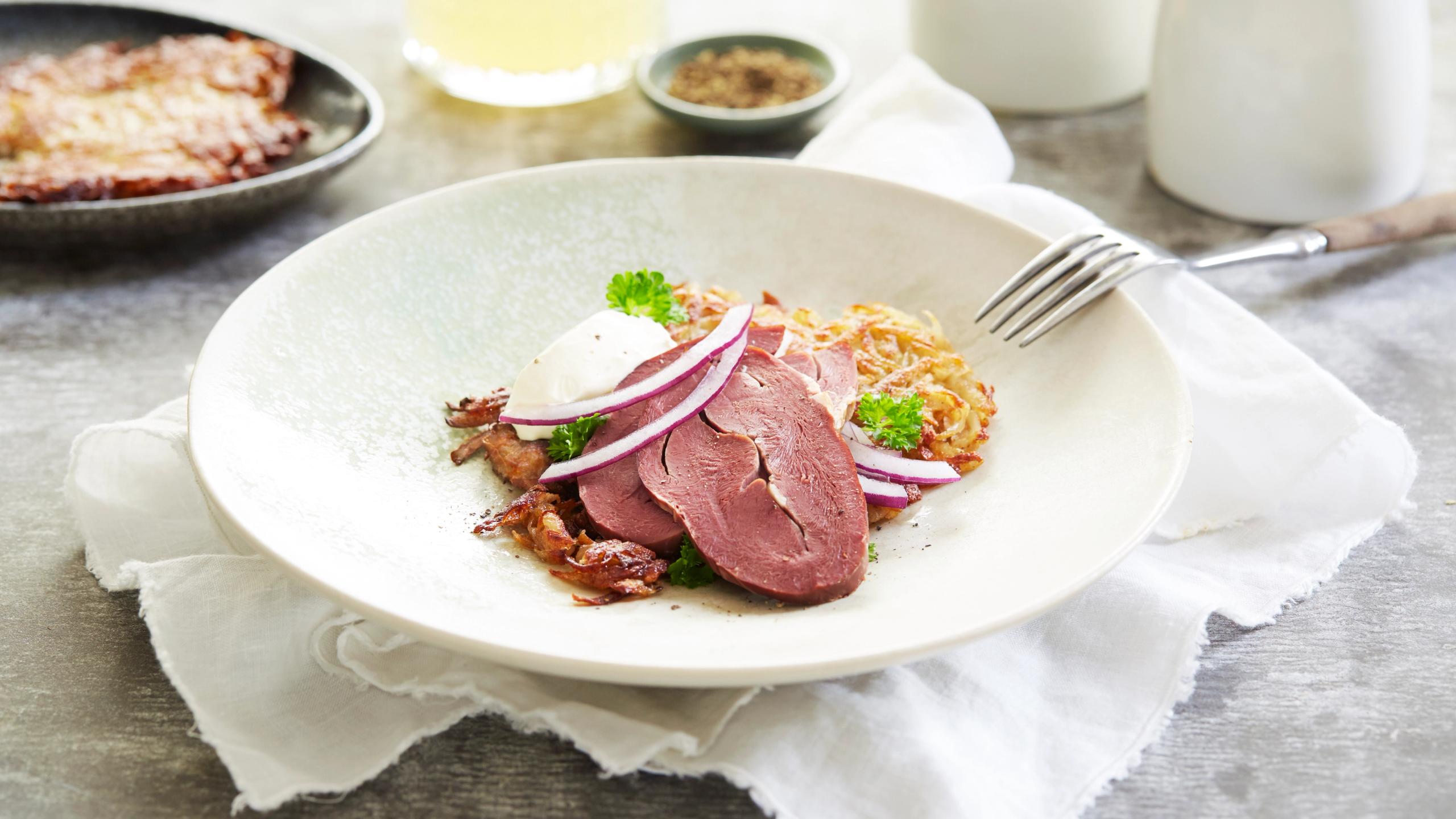 A bowl of smoked reindeer heart served with potatoes and salad in Norway