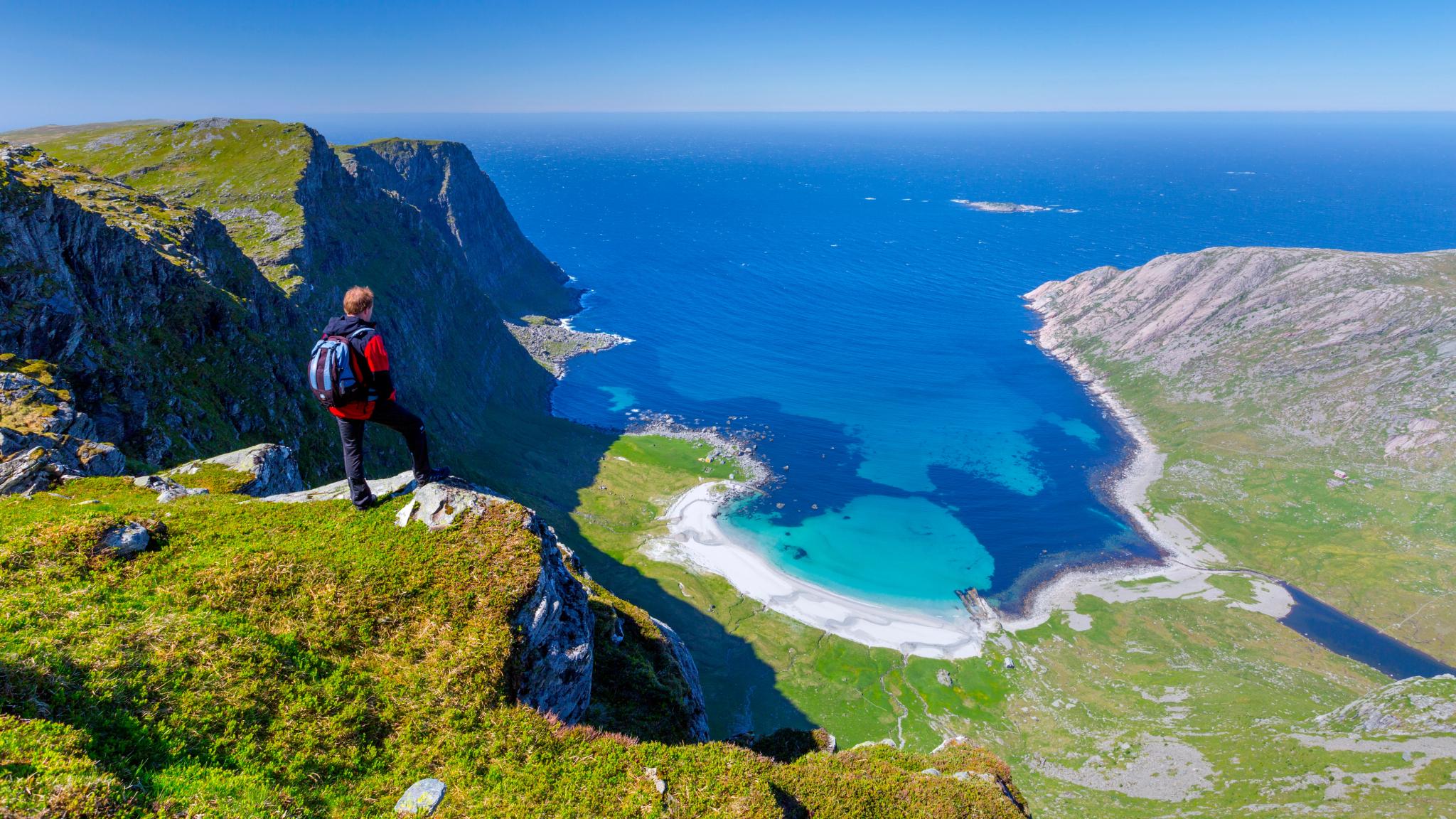 En man som står på ett berg ovanför den vackra stranden Vetvika i Fjord Norge