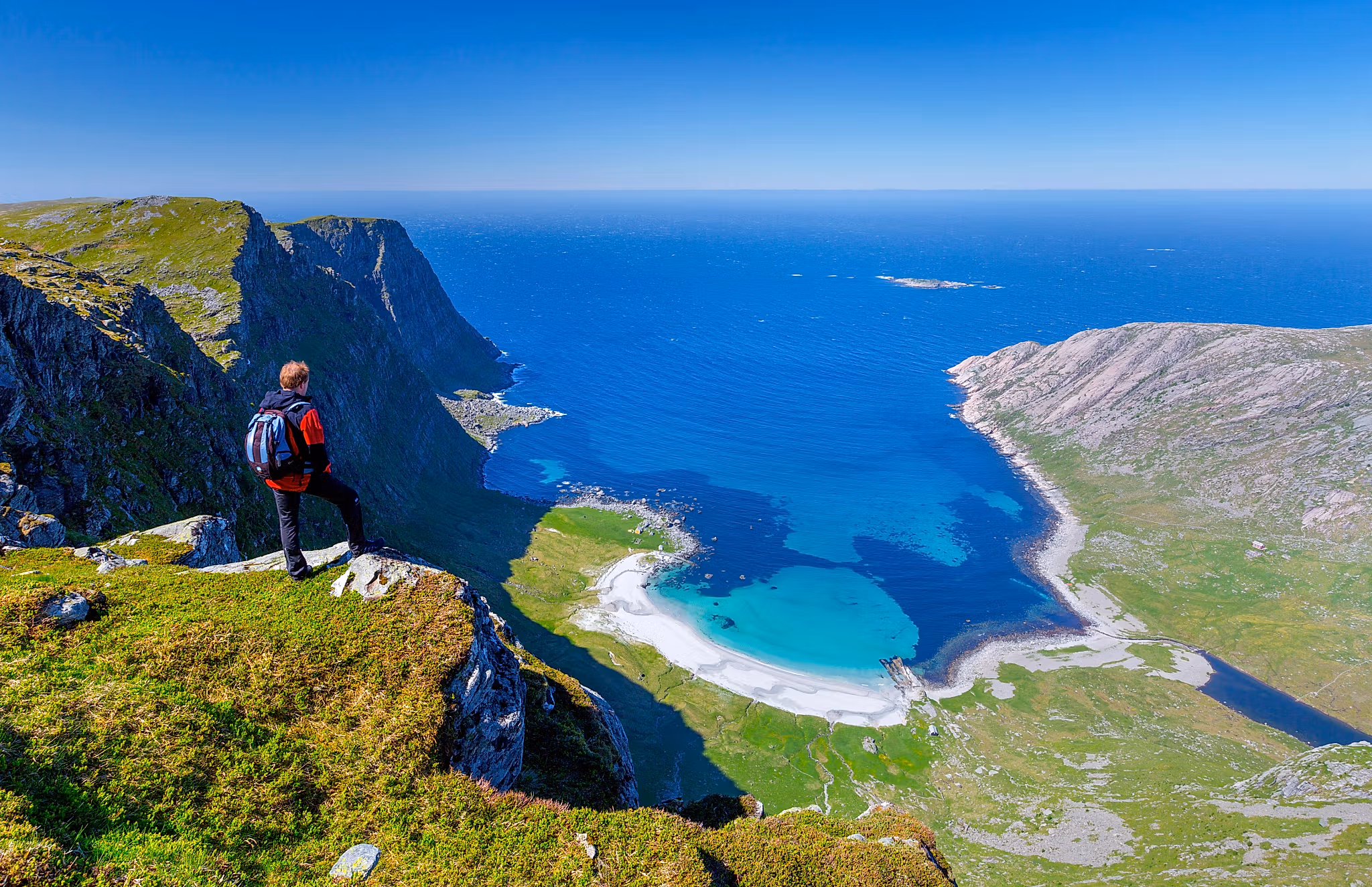 Man standing on the mountain above the beautiful Vetvika beach in Fjord Norway