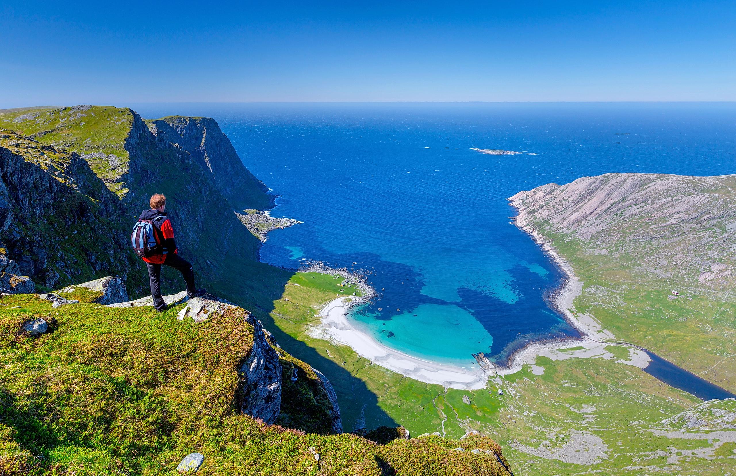 Man standing on the mountain above the beautiful Vetvika beach in Fjord Norway