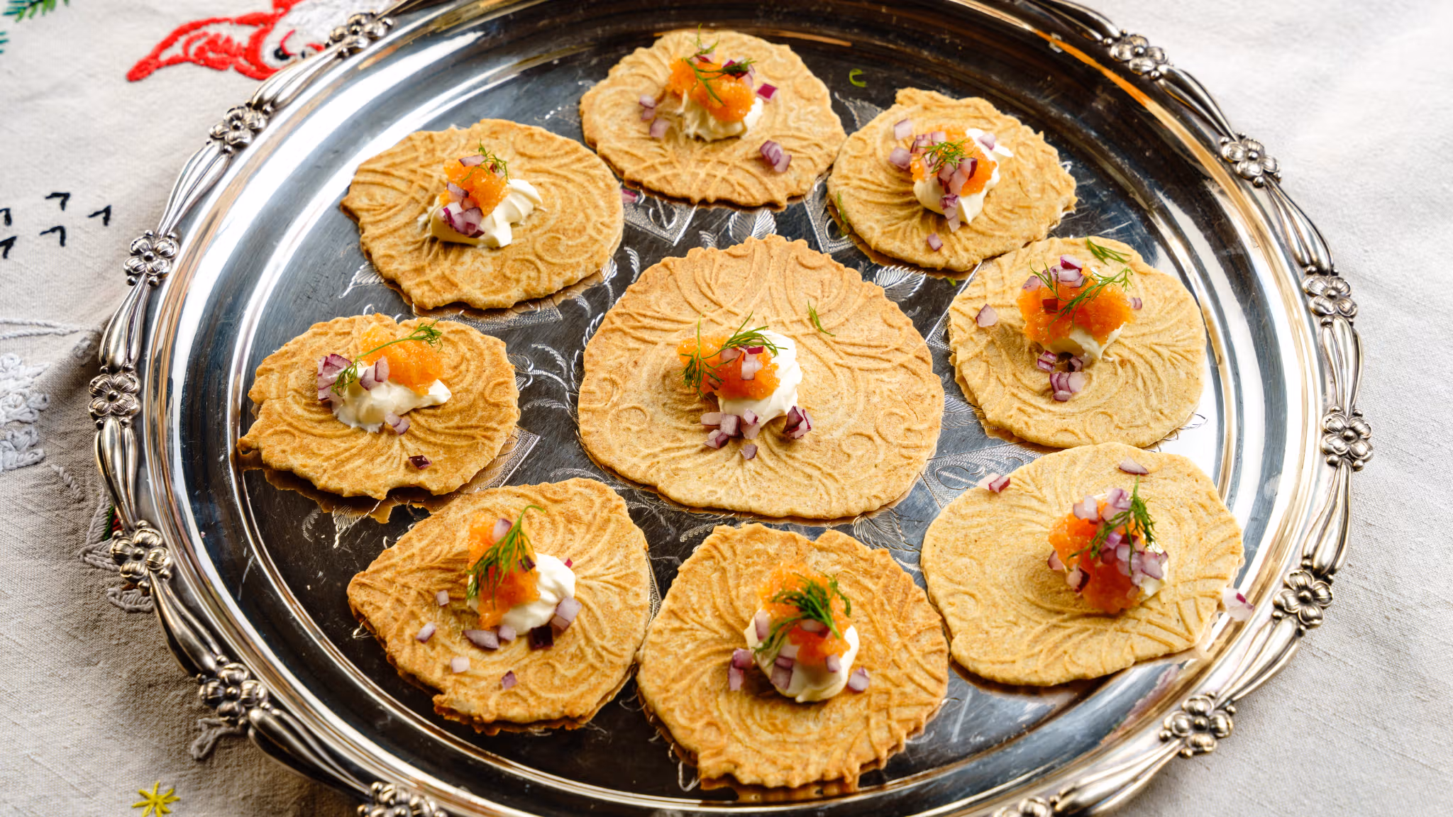 Krumkaker on a silver plate with salmon roe and sour cream.