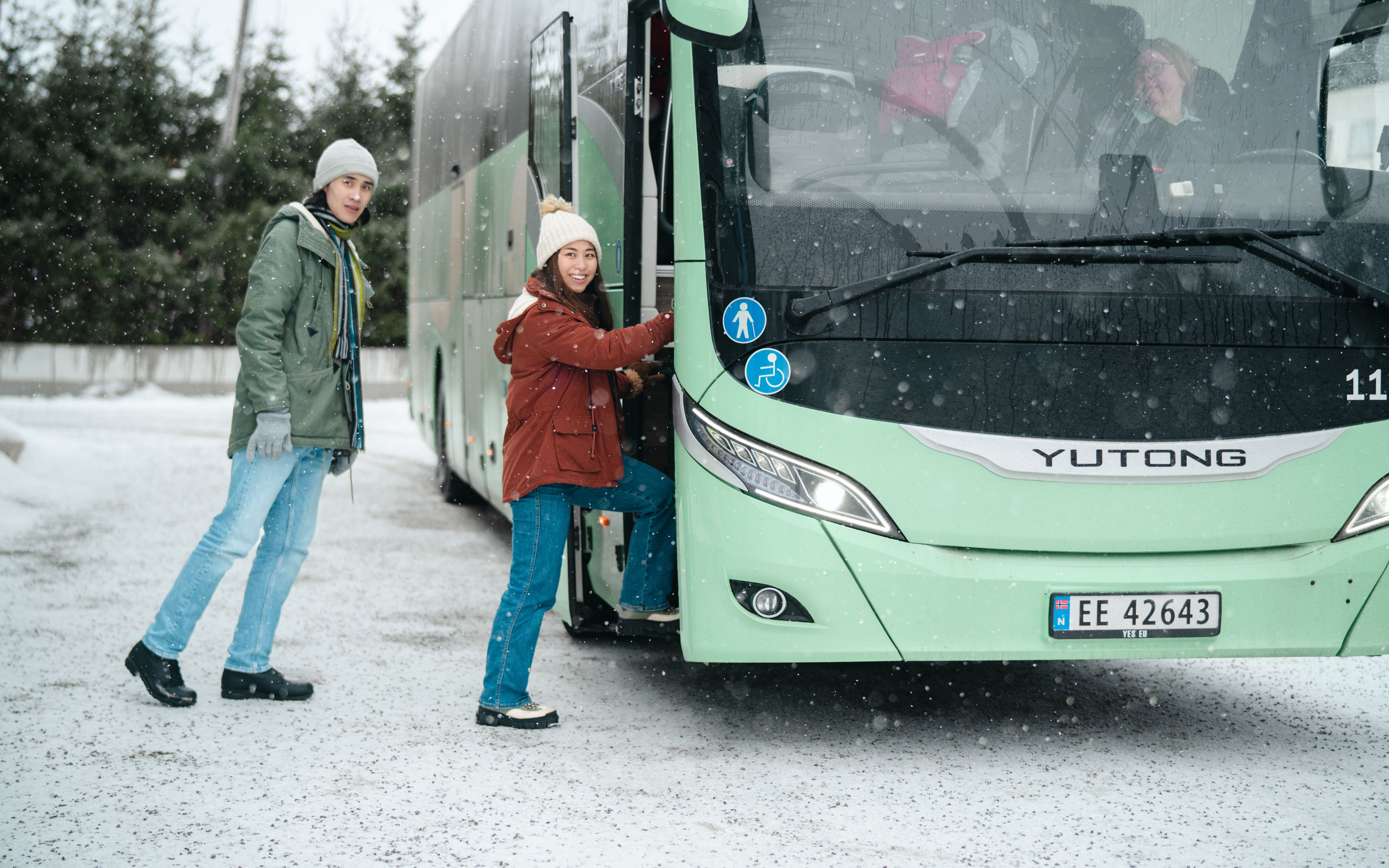 A man and a woman are going on a bus in Northern Norway in winter landscape.