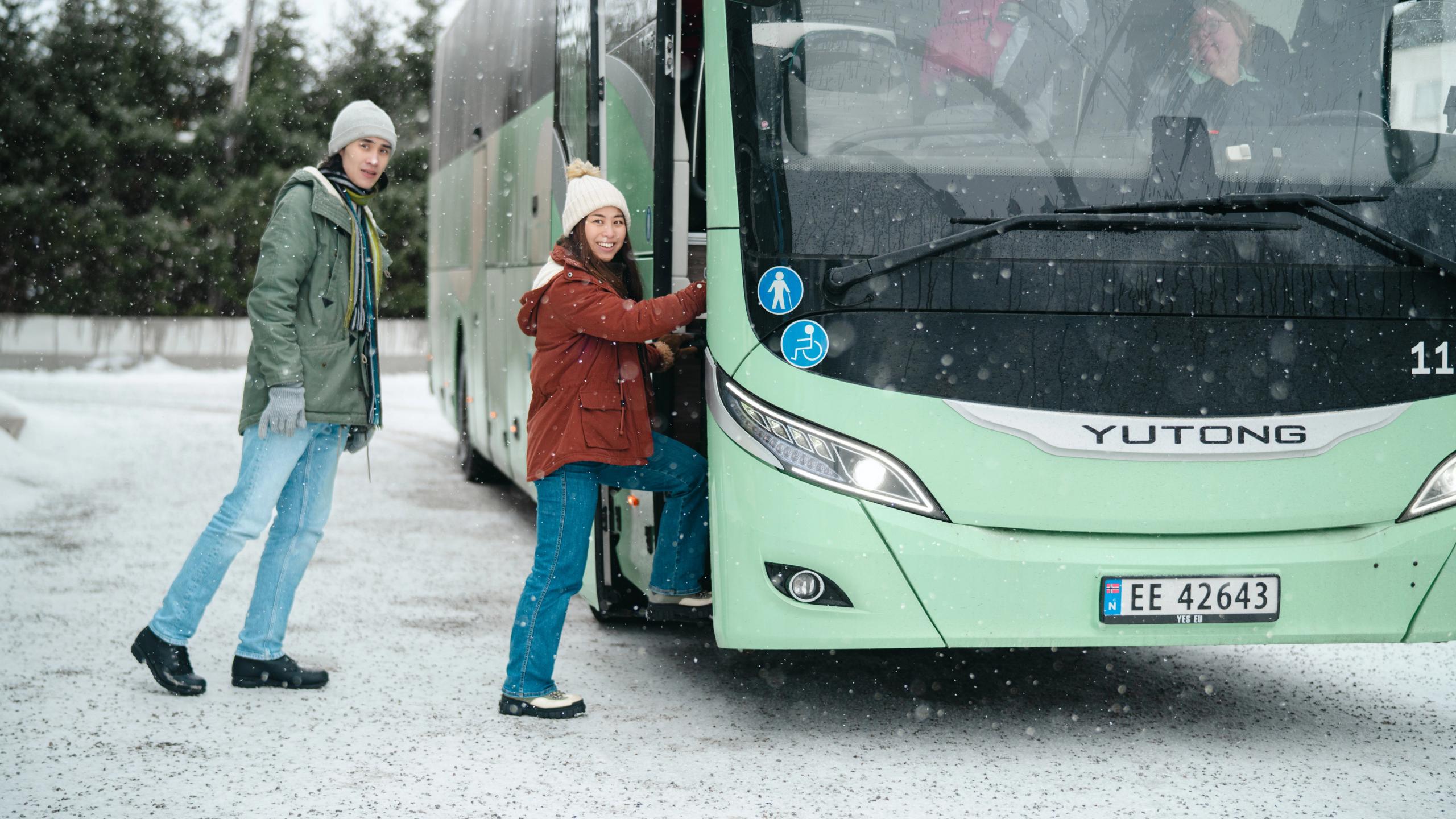 A man and a woman are going on a bus in Northern Norway in winter landscape.