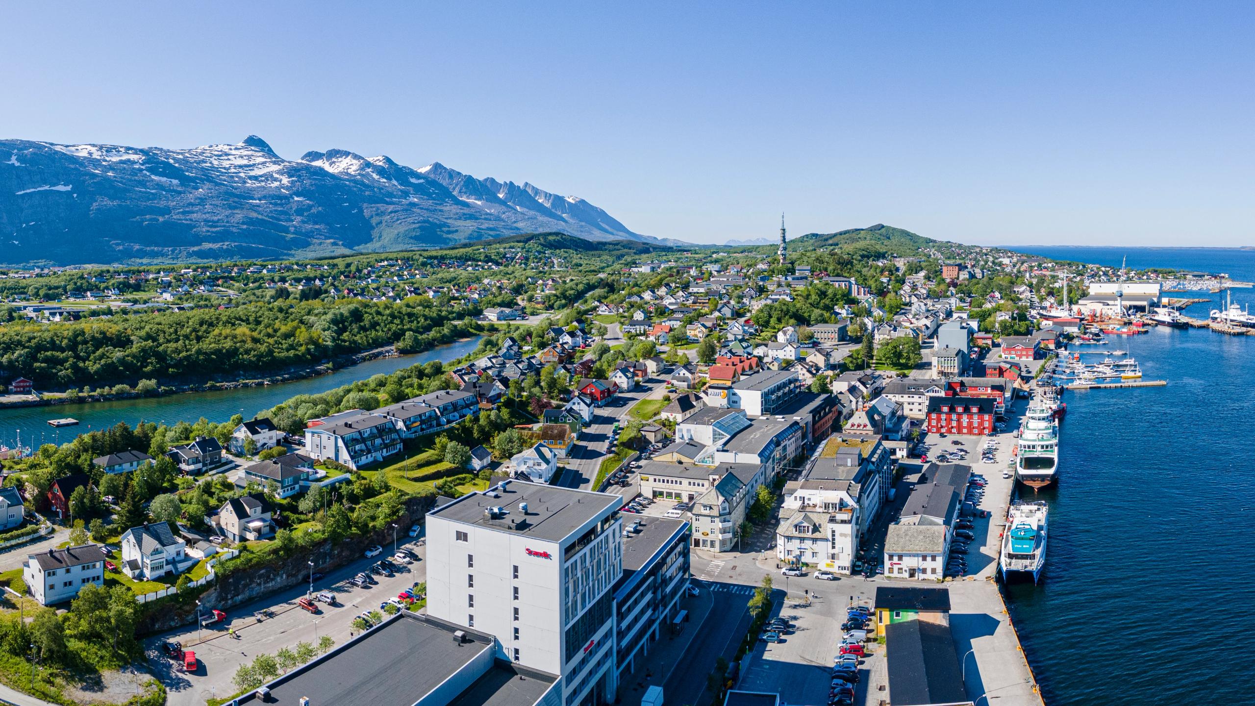 A panoramic view of a coastal city including mountains and the harbour.