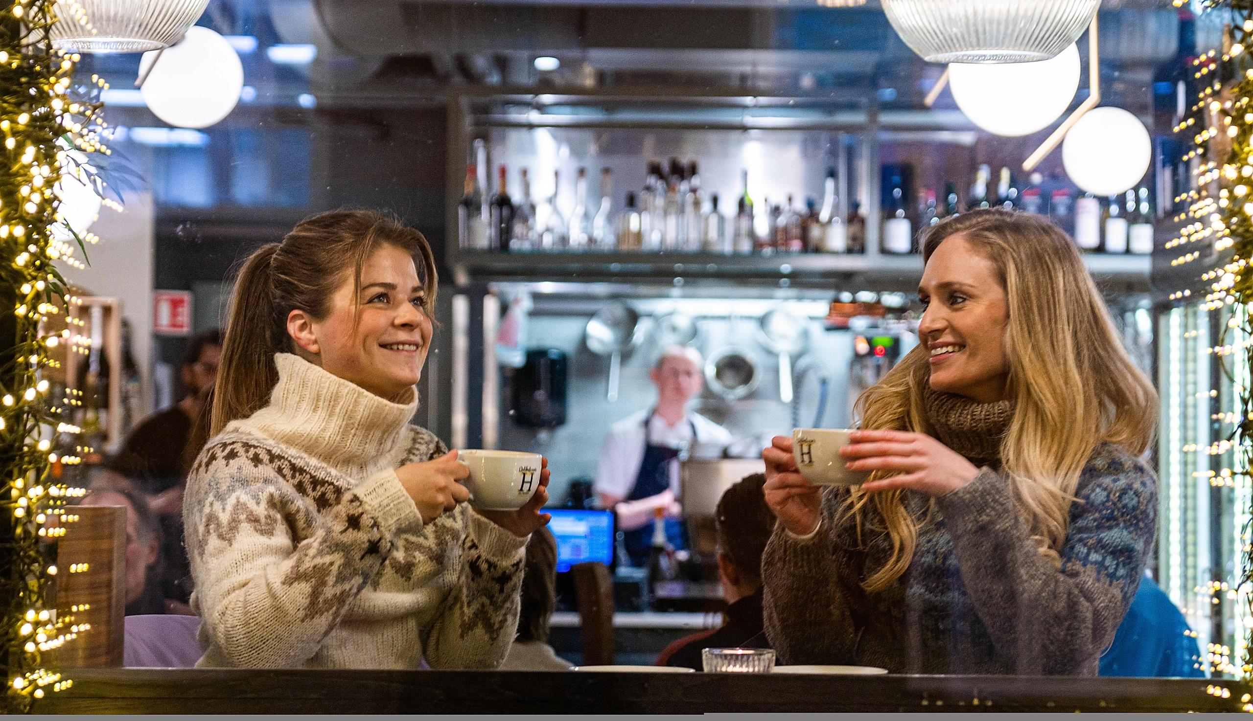 To jenter nyter en kopp varm kakao på Helmersen Delikatesser & Vinbar i Tromsø