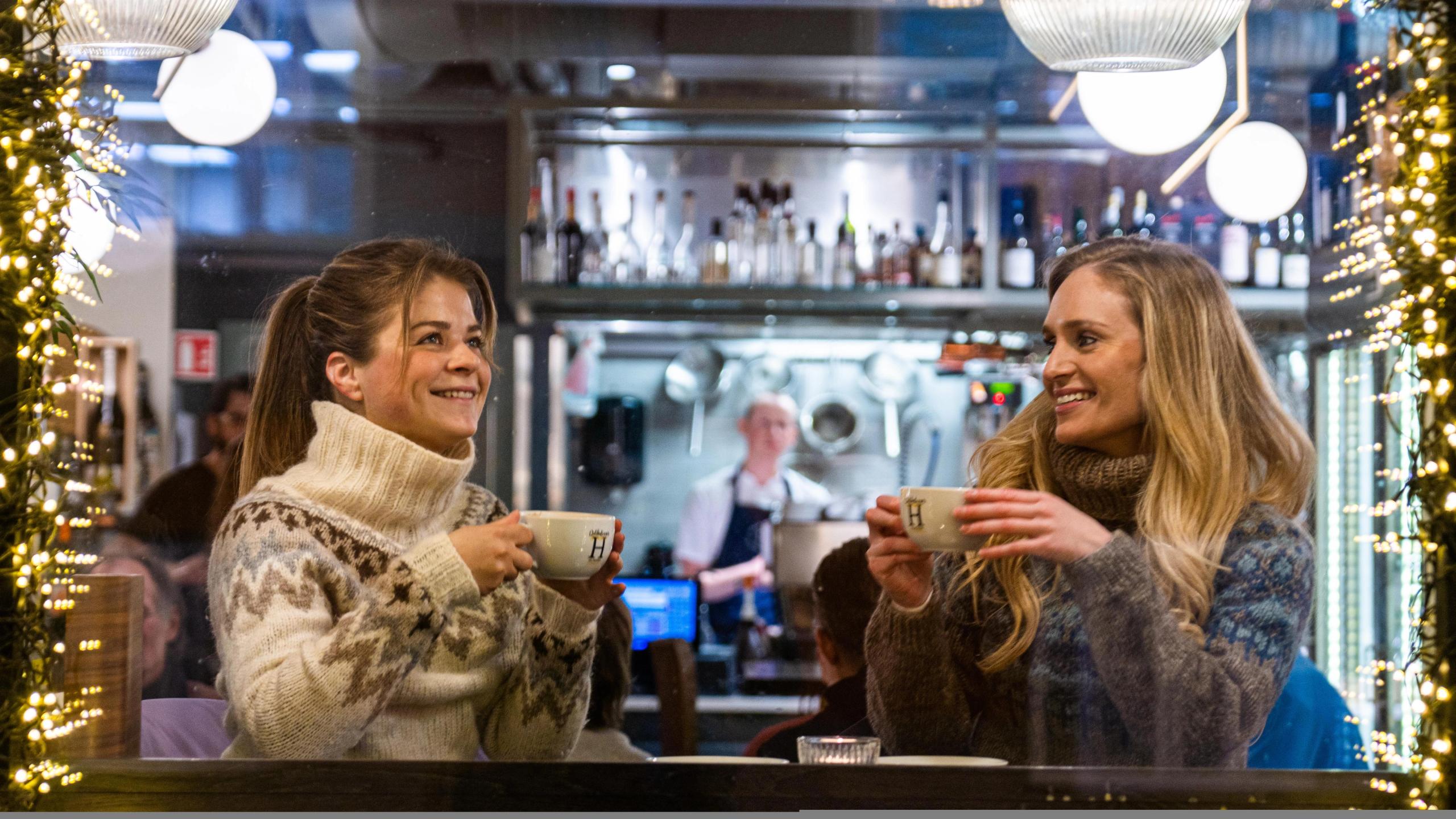 Two girls enjoying hot chocolate at a café.