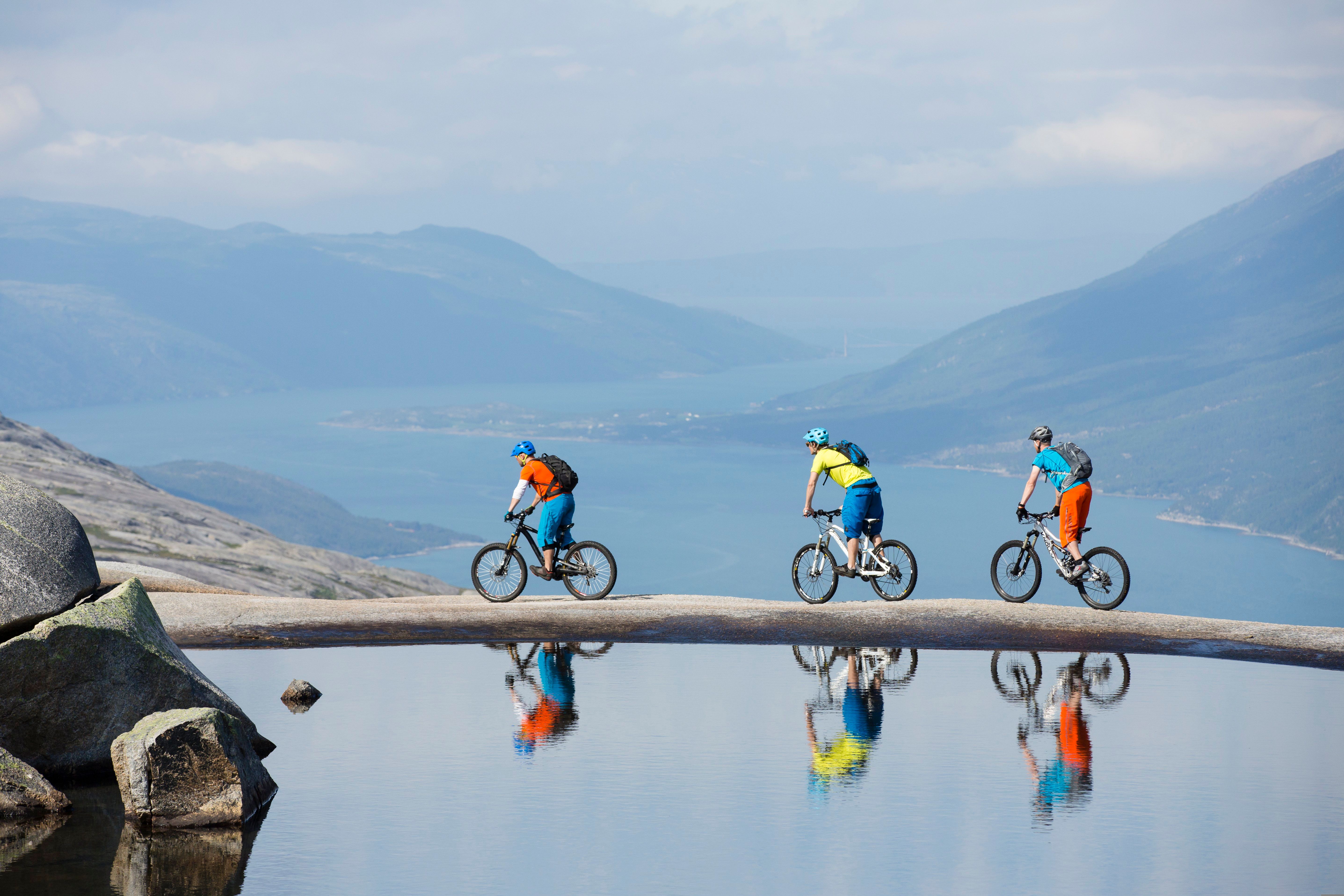 Drie mensen aan het mountainbiken langs een smal meer in de Reinnesfjellet-bergen in Narvik, Noord-Noorwegen