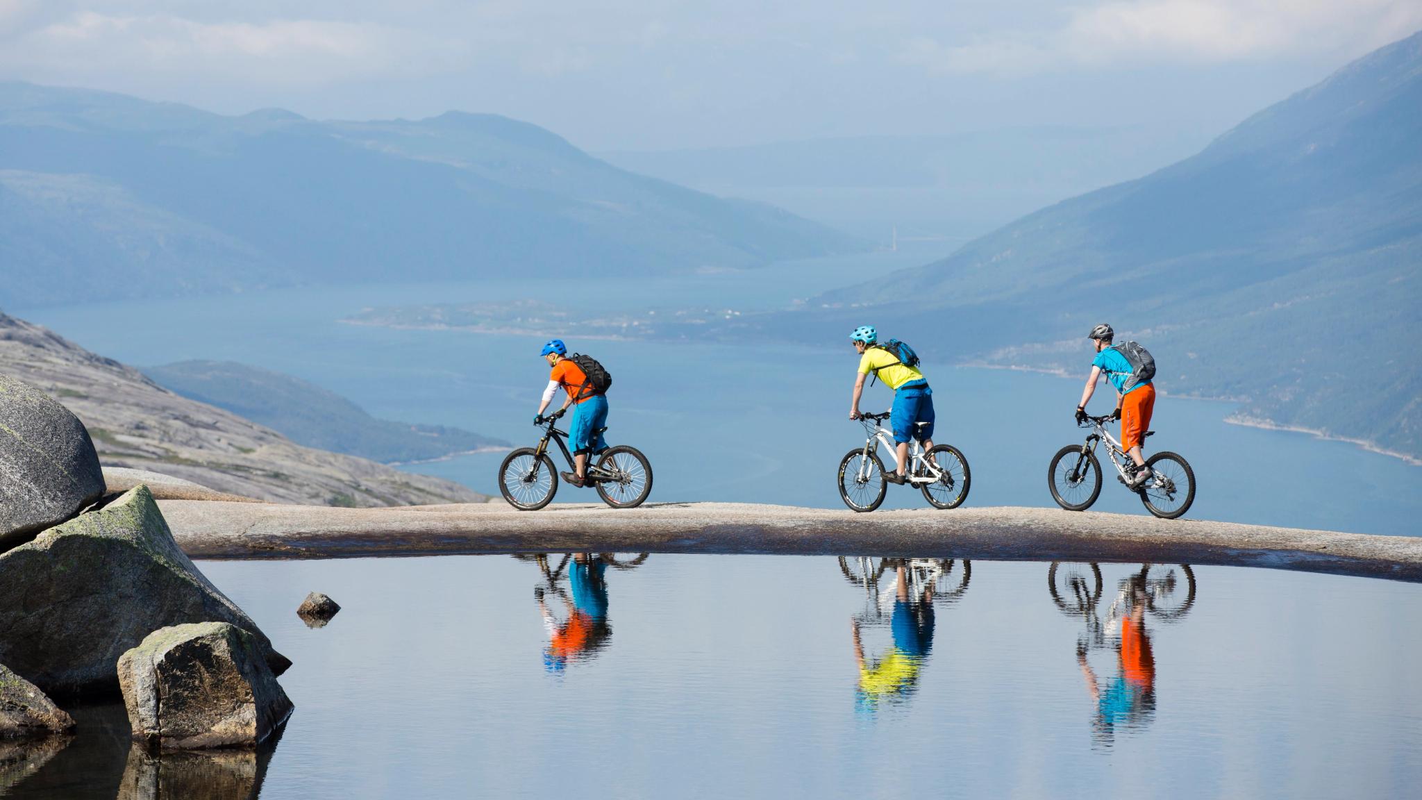 Drie mensen aan het mountainbiken langs een smal meer in de Reinnesfjellet-bergen in Narvik, Noord-Noorwegen
