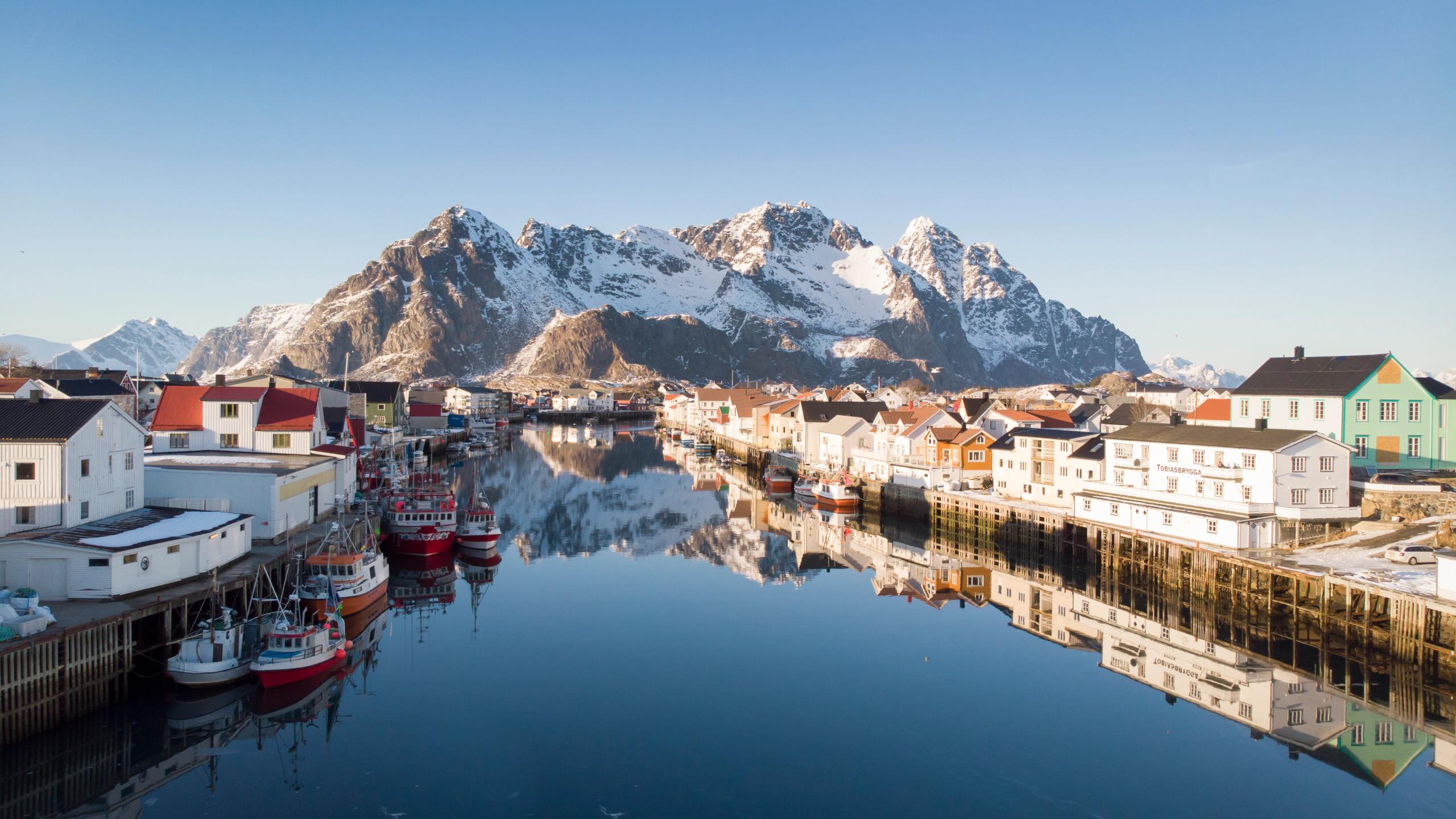 Wooden houses, fishing boats and snowcapped mountains, Henningsvær in certified Sustainable Destination Lofoten, Northern Norway
