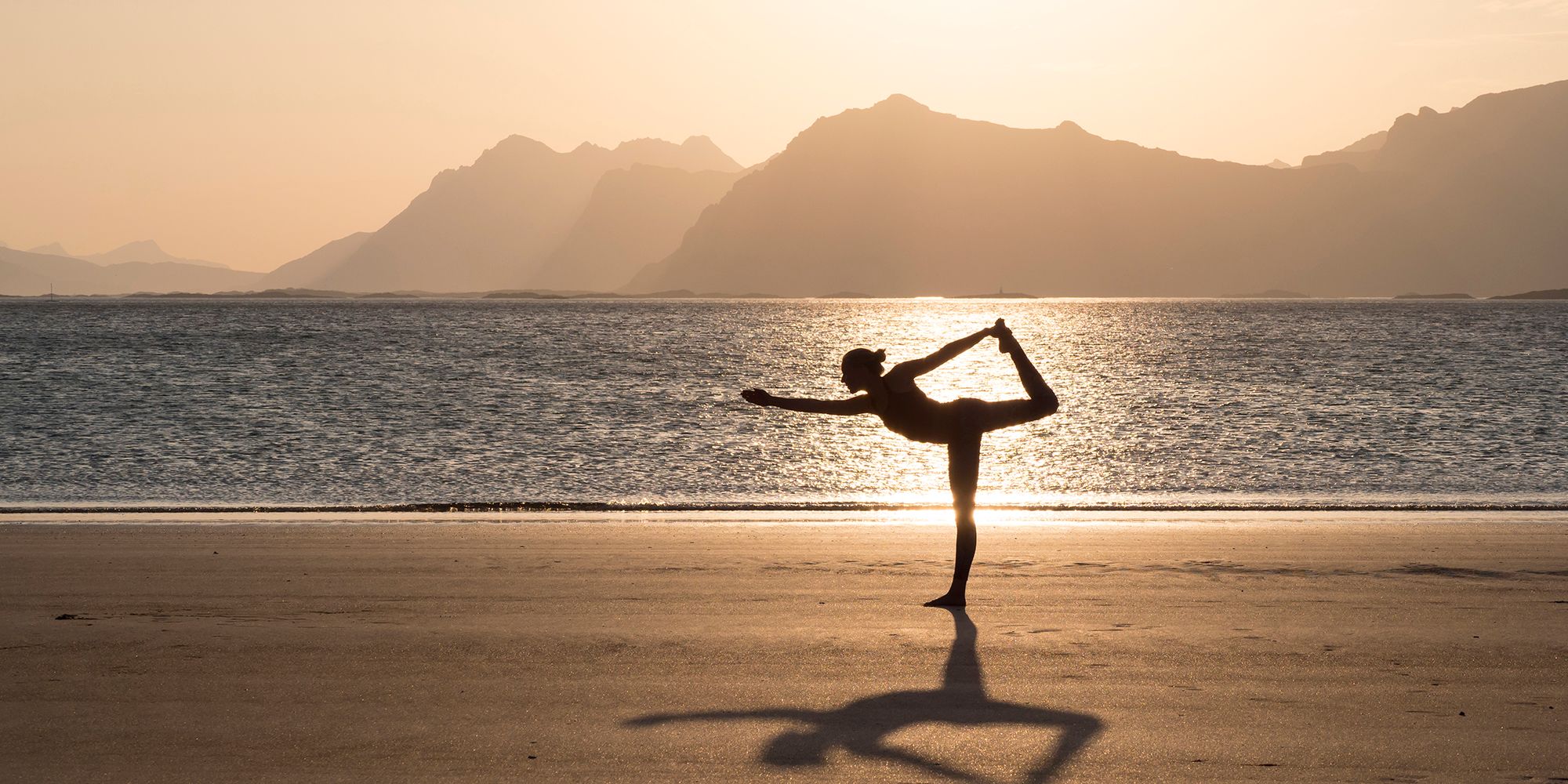 A women practicing yoga in silence on the beach in Lofoten, Northern Norway