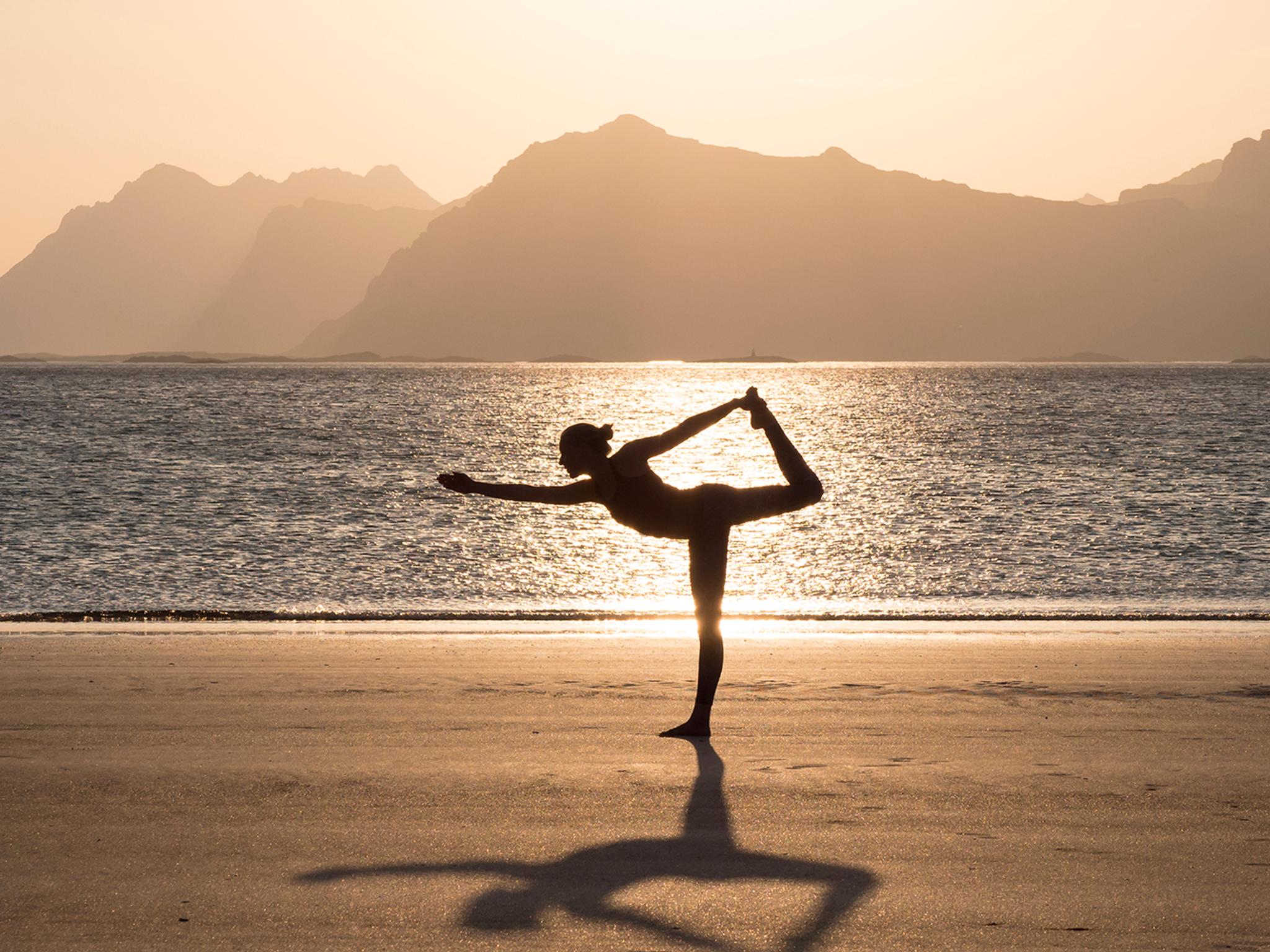 A women practicing yoga in silence on the beach in Lofoten, Northern Norway