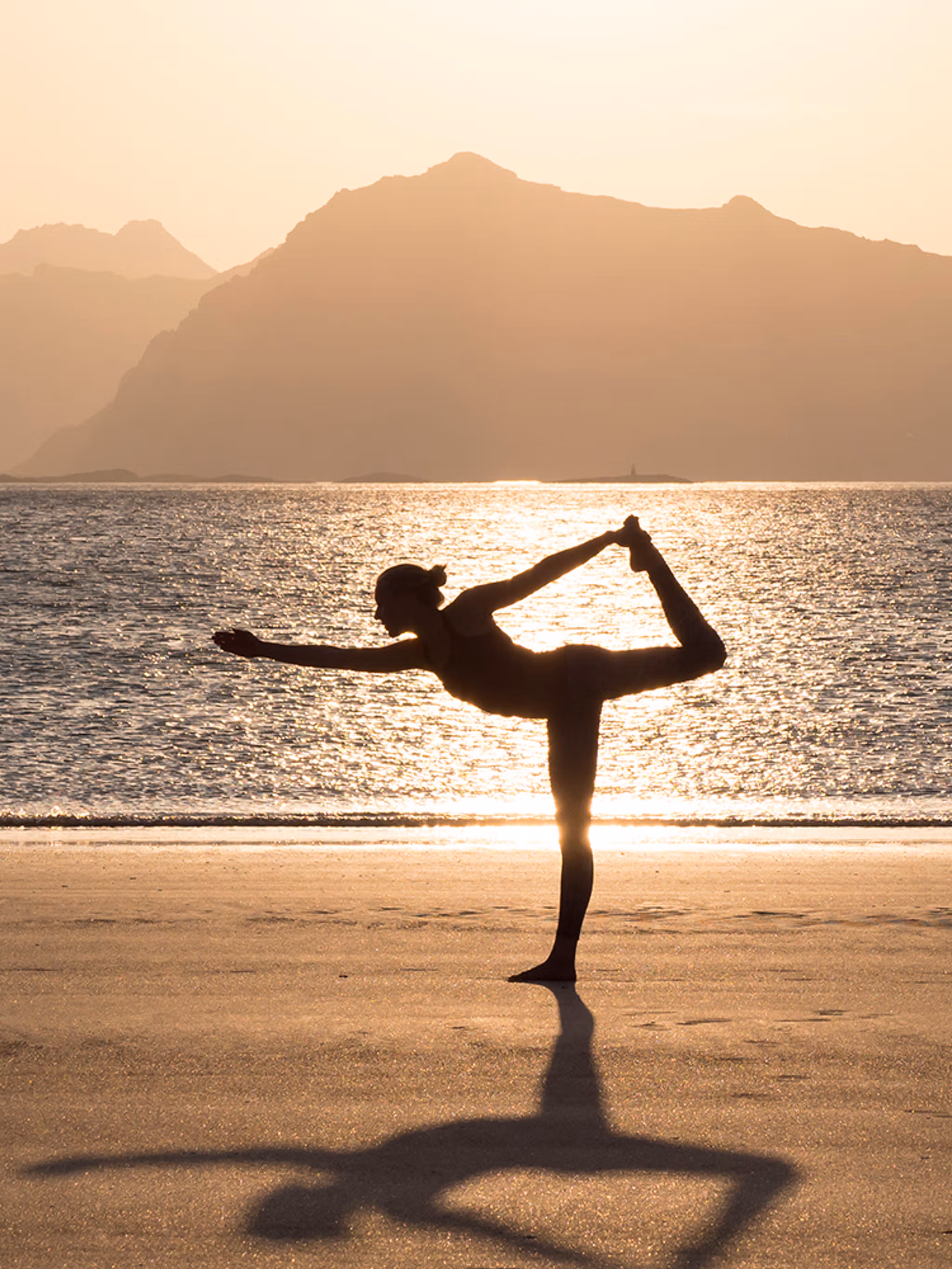A women practicing yoga in silence on the beach in Lofoten, Northern Norway