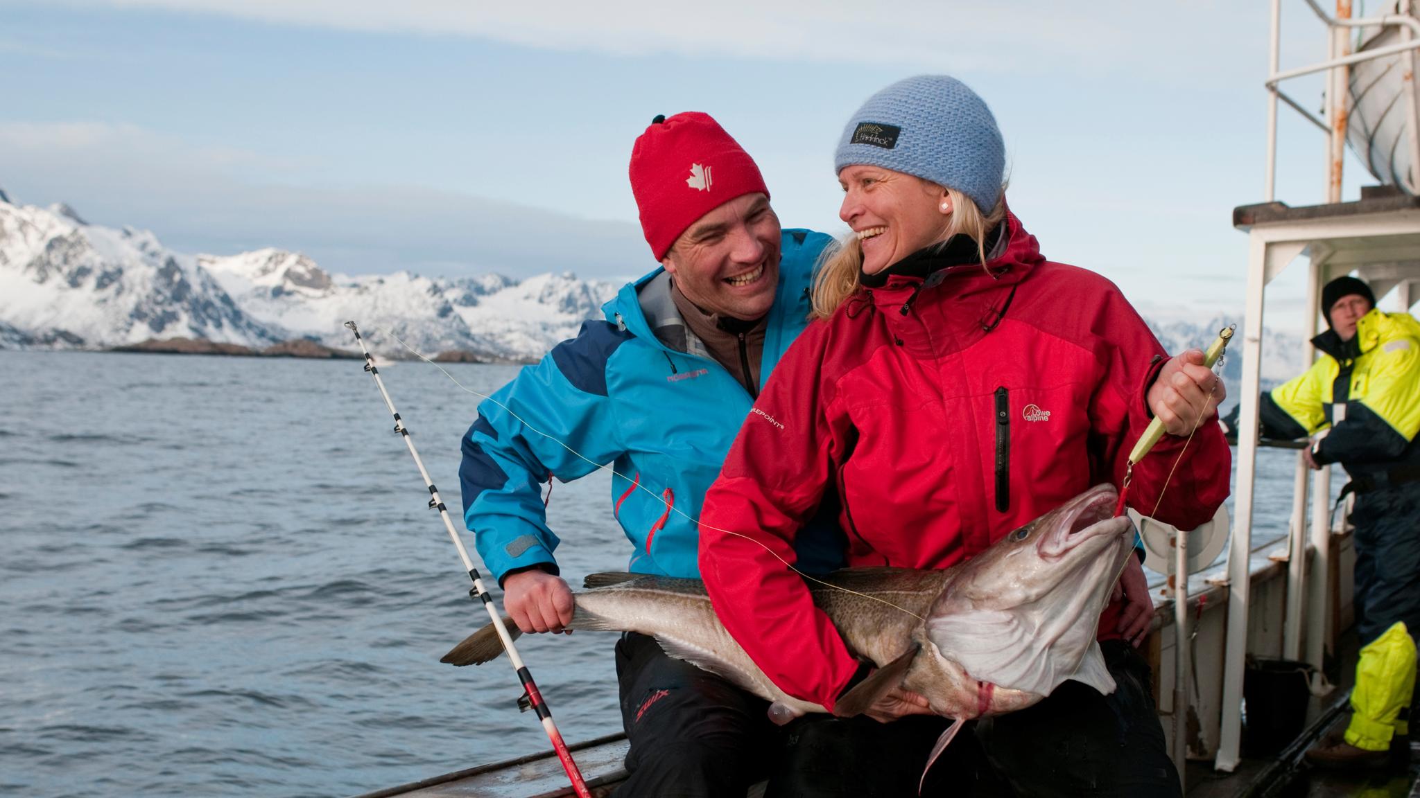 A woman and a man holding a newly caught cod in Lofoten in Northern Norway
