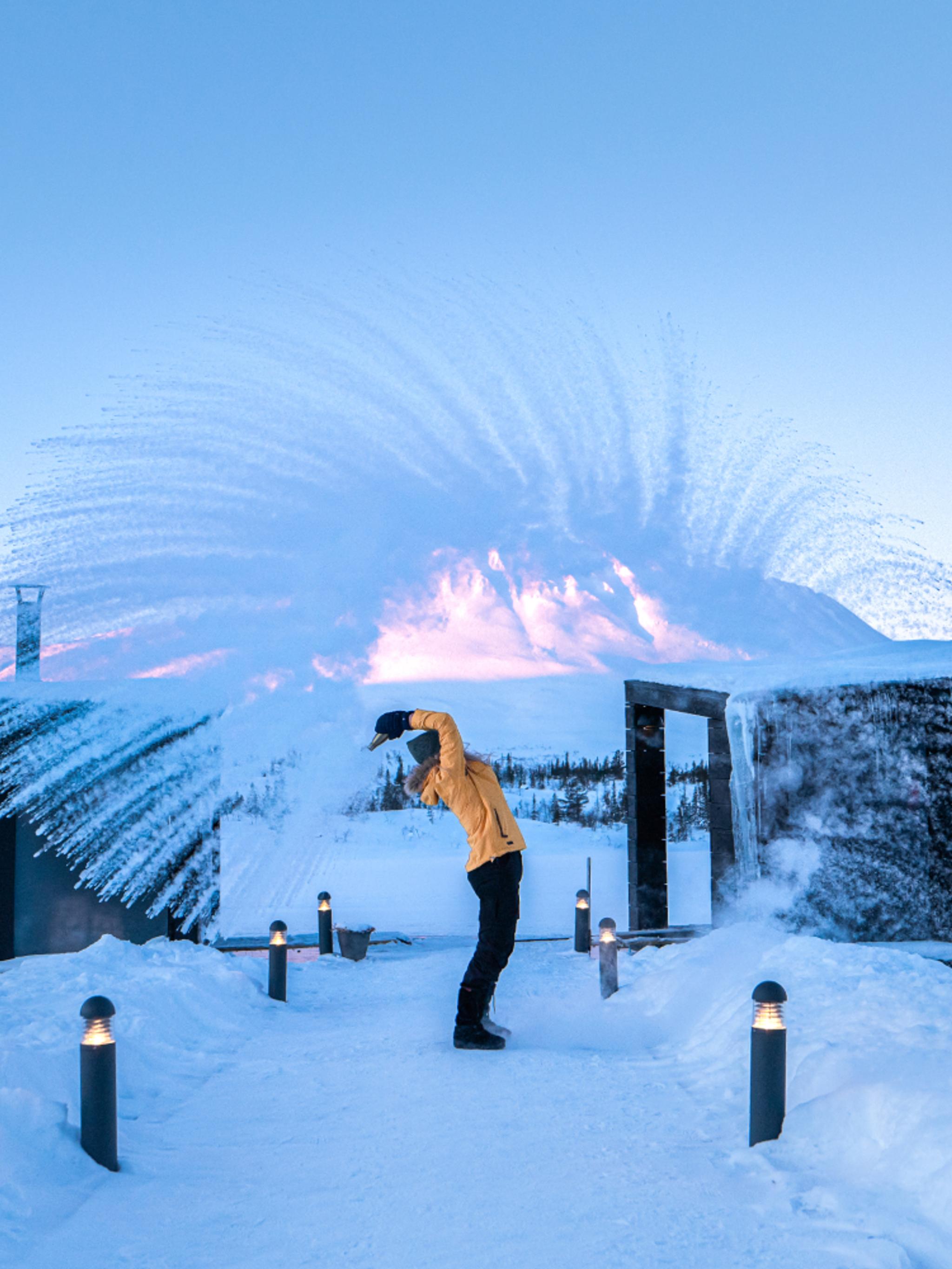 En jente kaster snø i luften foran to flytende saunaer på Gausta, Telemark