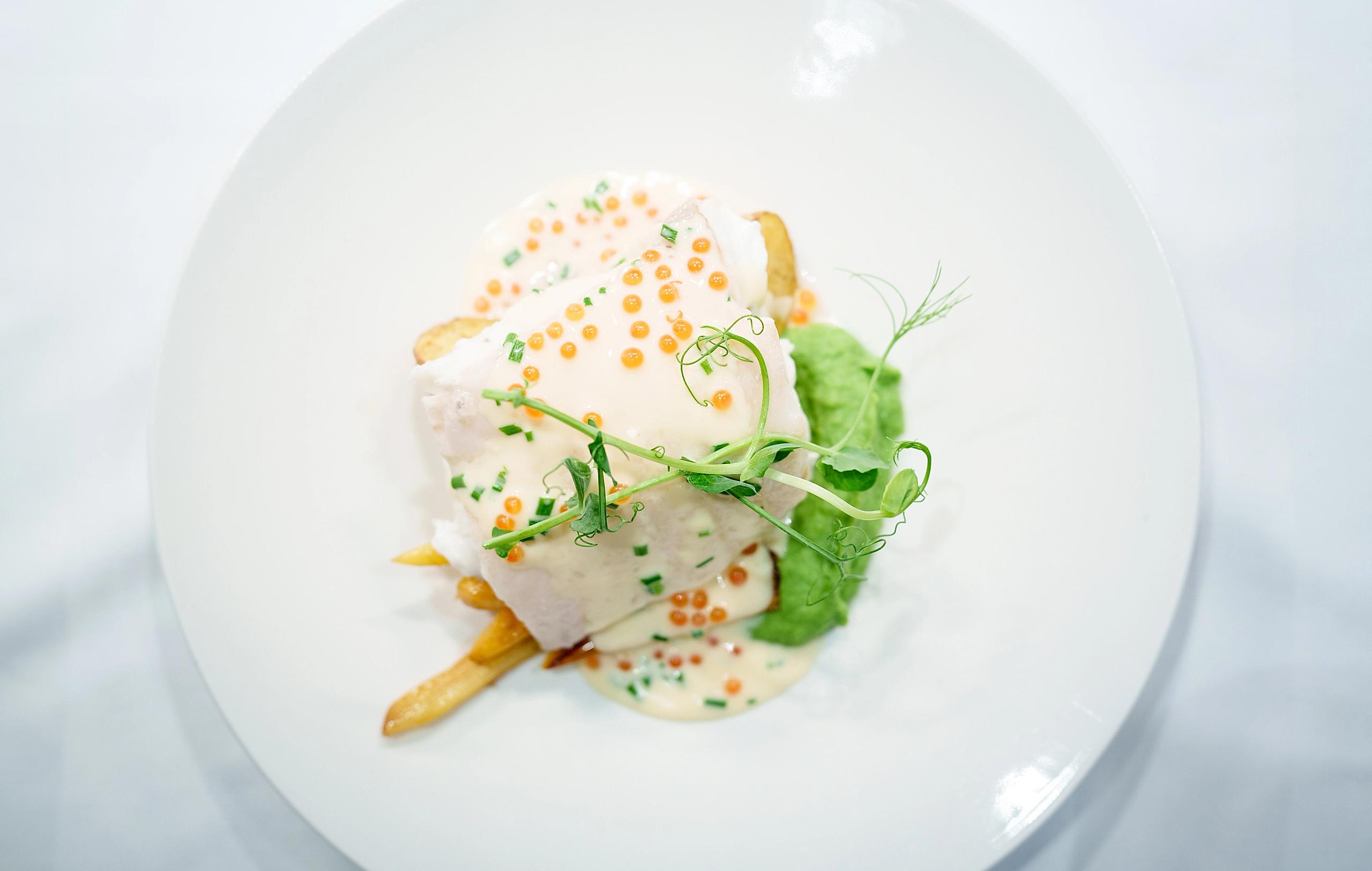 En fint anrettet tallerken med kveite, potet, ertepuree og hvit saus