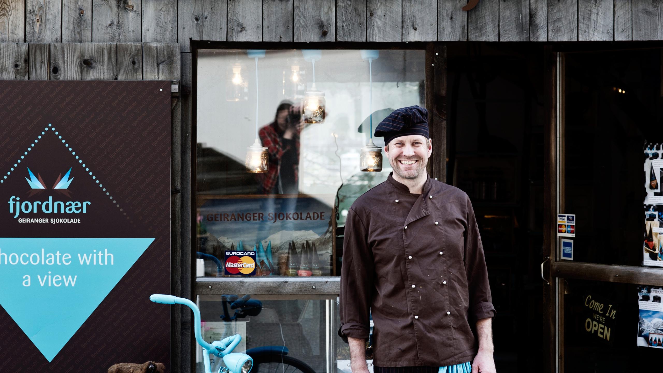 A man standing outside of the Geiranger chocolate factory, Norway.