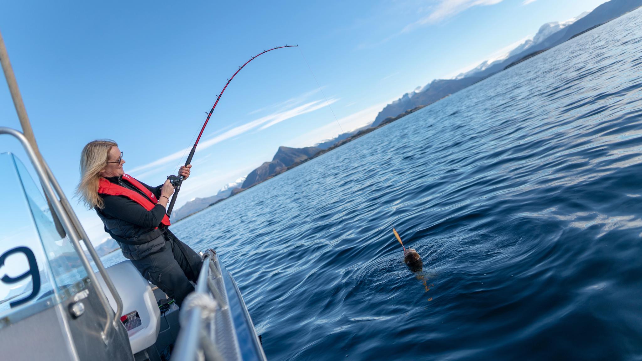 Una mujer pesca desde una barca frente a la costa de Bolga. en Helgeland, Norte de Noruega.