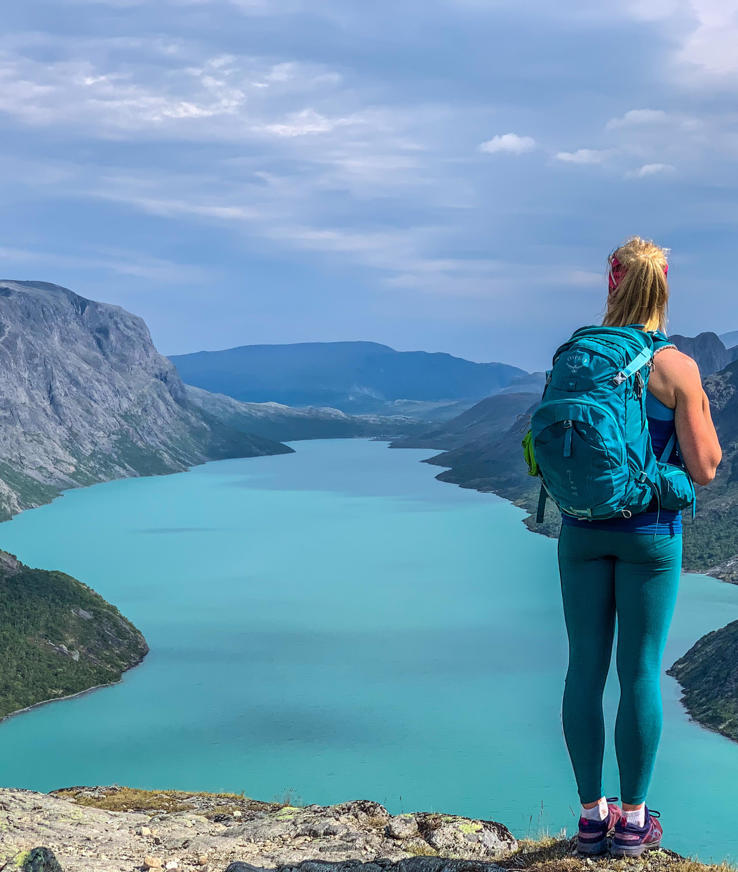 A woman looking a the view of a lake from the top of a mountain