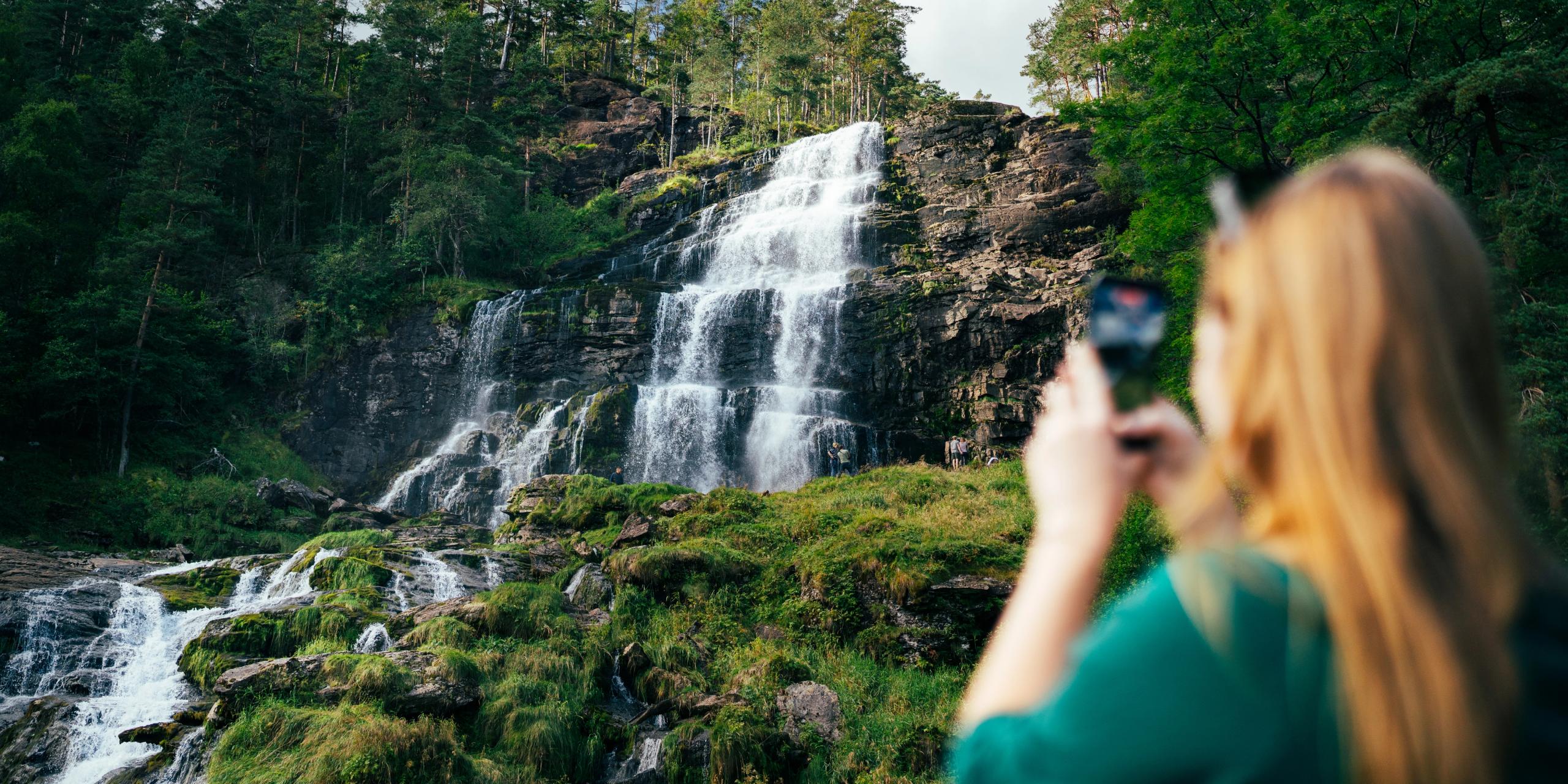 People taking pictures of a waterfall.