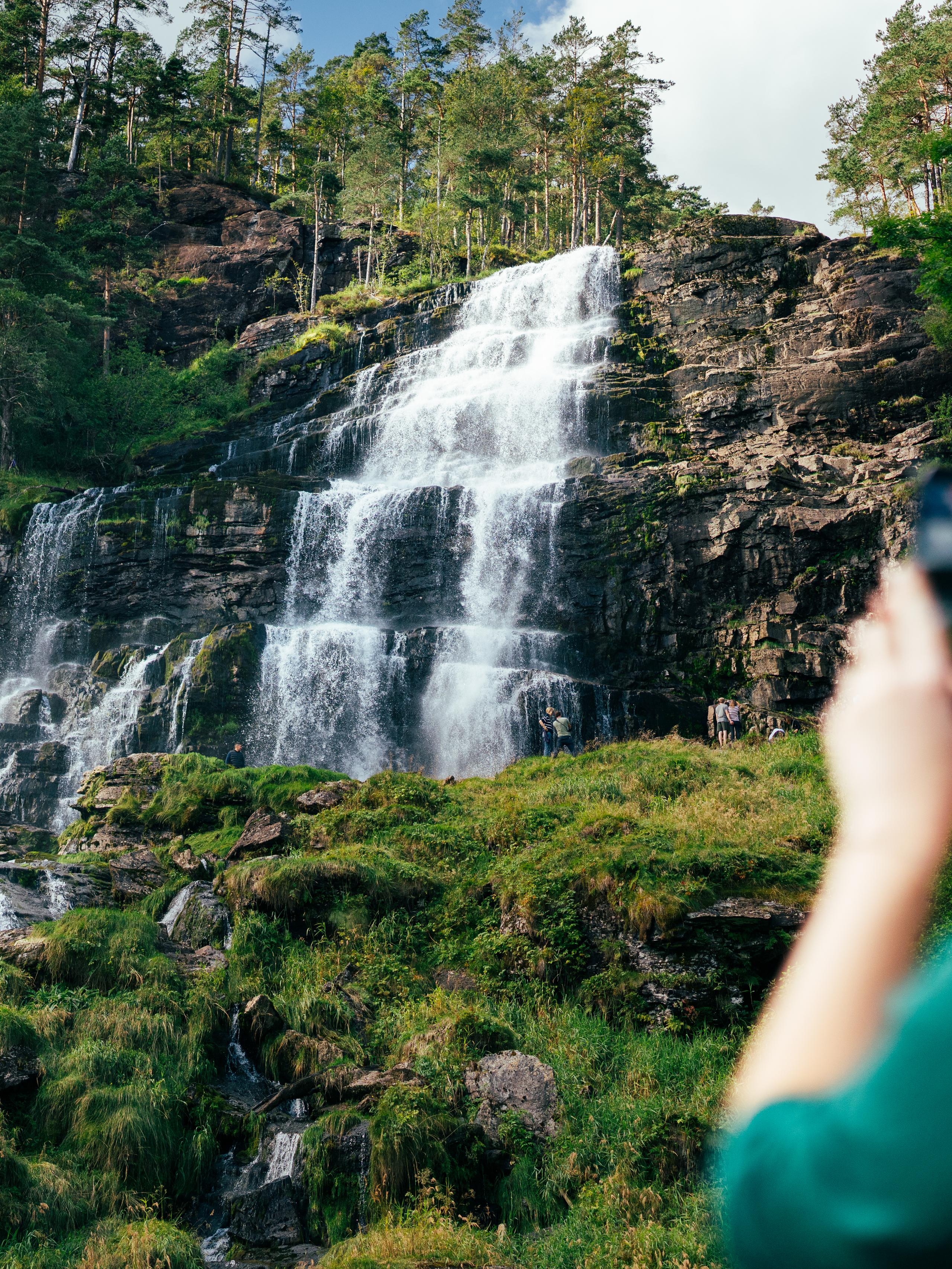 People taking pictures of a waterfall.