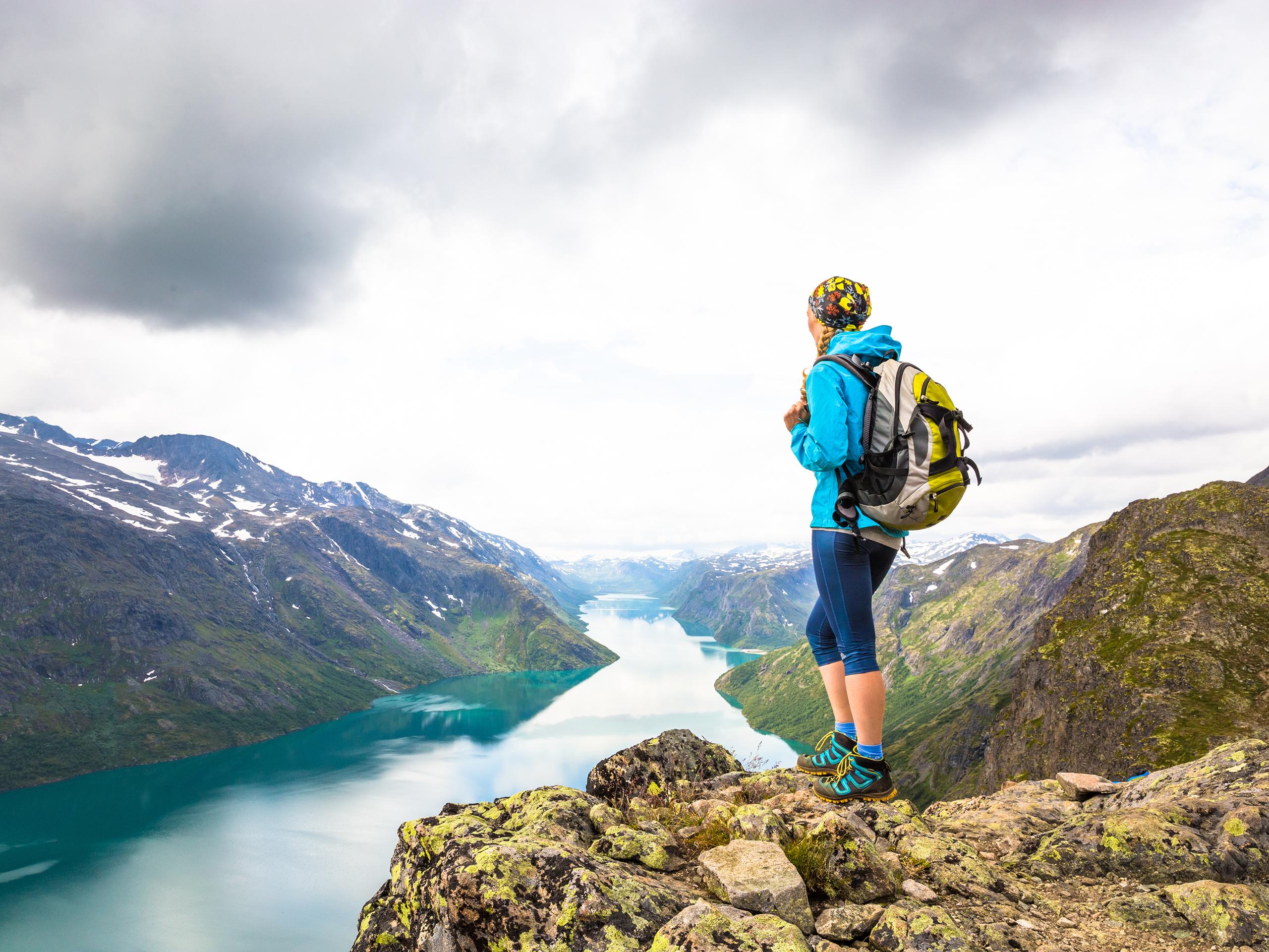 En dame står på toppen av Besseggen og ser utover Gjende i Jotunheimen