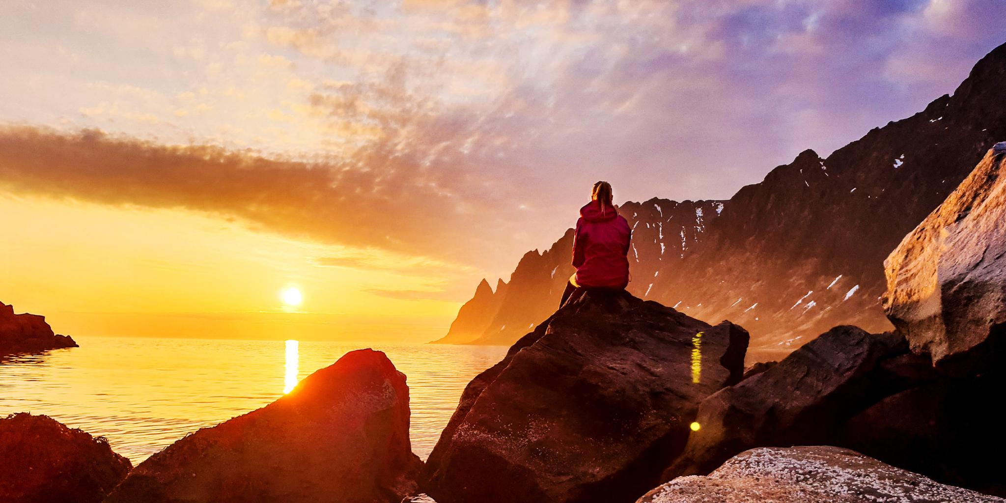 En person tar in midnattssolen i Senja i Nord-Norge