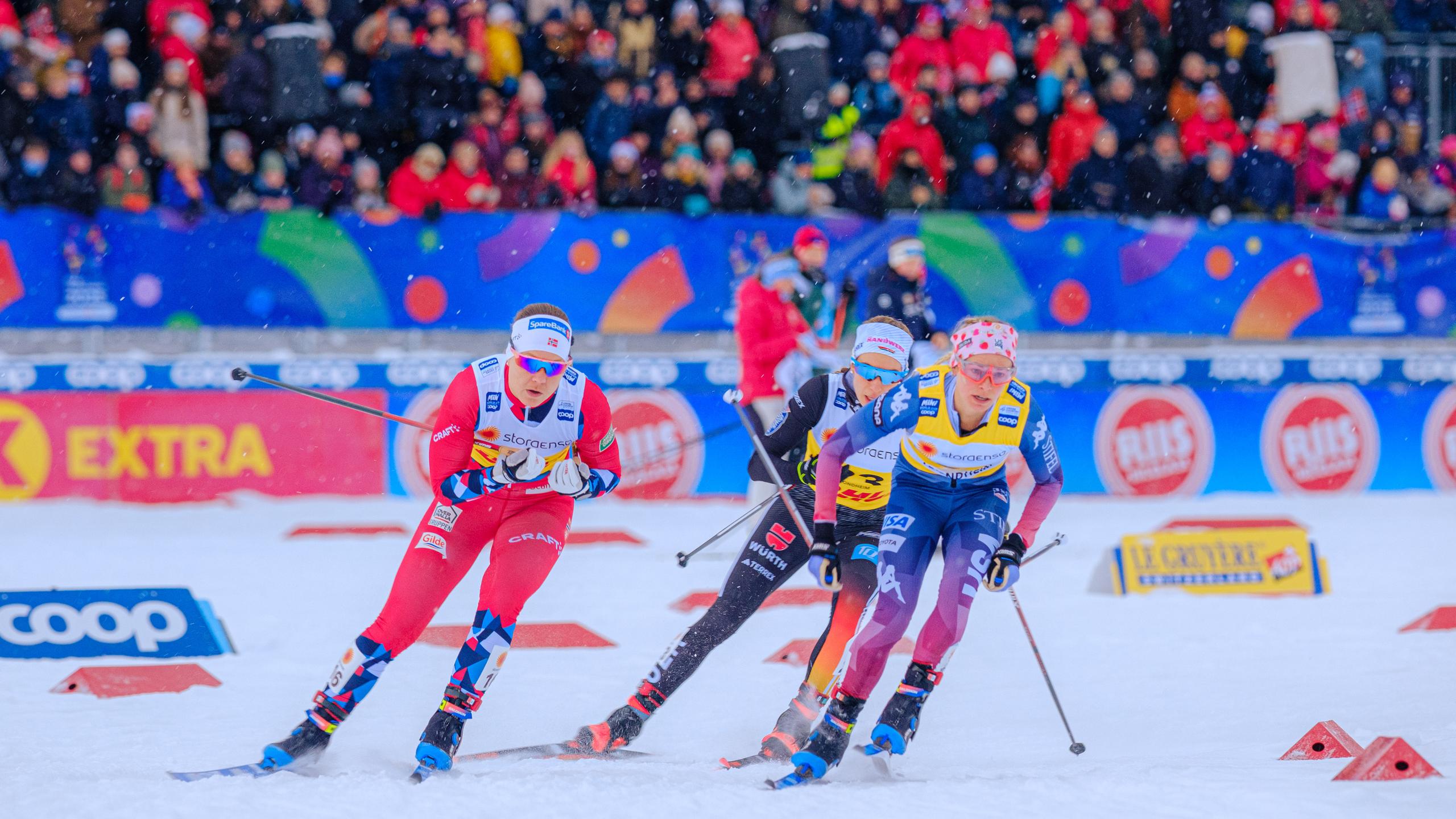Woman in a skiing competition in front of a stand full of people.