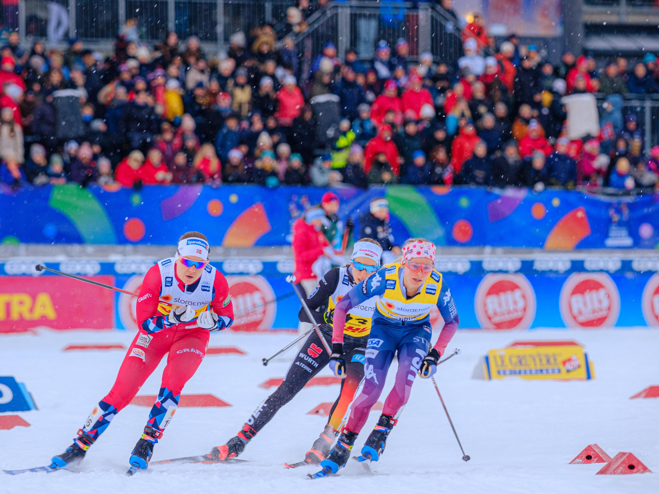Woman in a skiing competition in front of a stand full of people.