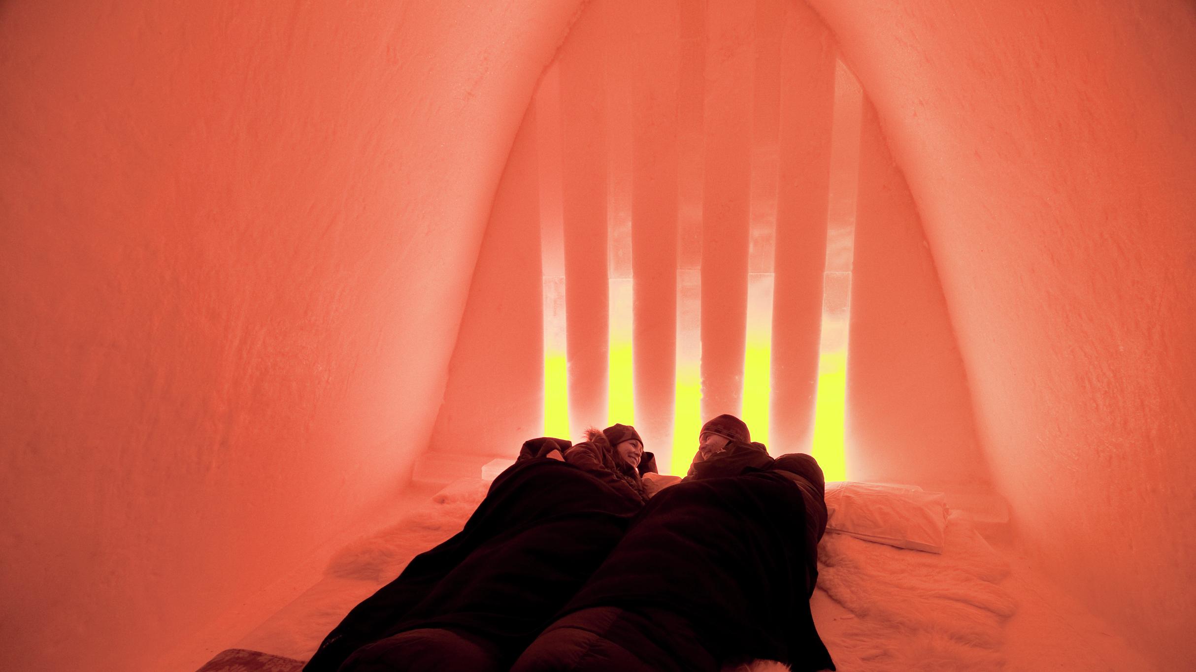Two people under raindeer skins in the Snow Hotel in Hunderfossen Winter Park, Eastern Norway