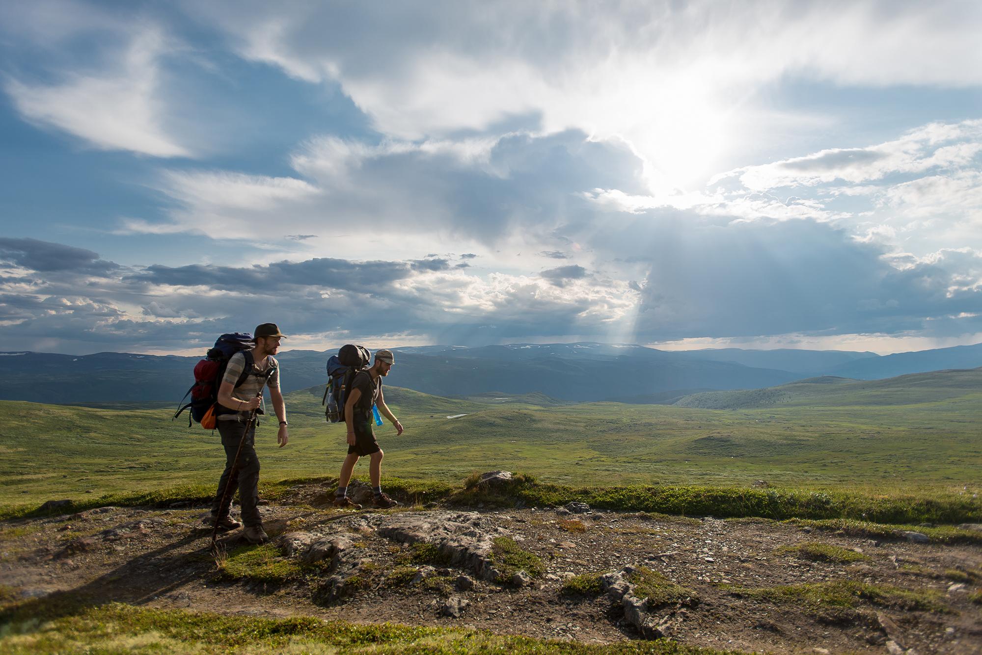 Two men wearing backpacks hiking the Gudbrandsdalen path, the pilgrim trail St. Olav Ways to Trondheim, across Dovrefjell in Eastern Norway
