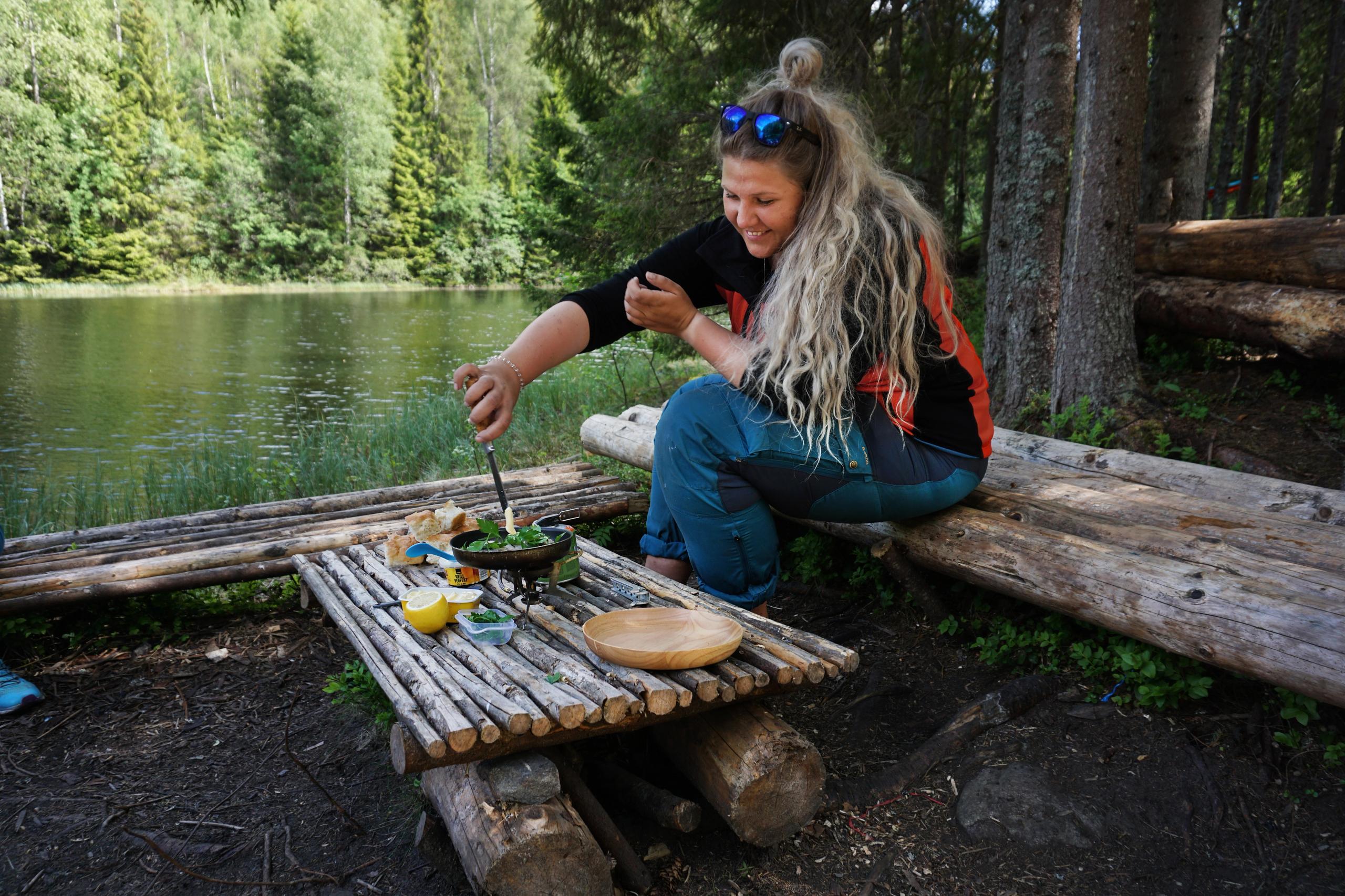 Eine Frau, die den Fang nach dem Süßwasserfischen kocht, an einem See in Akershus, Ostnorwegen.