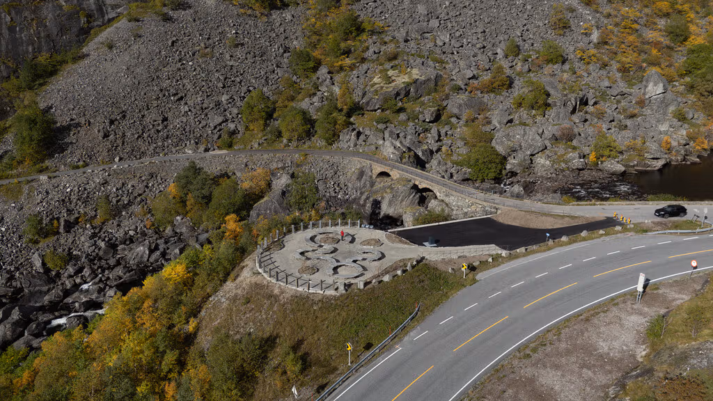 A rest stop with benches right by an old stone bridge.