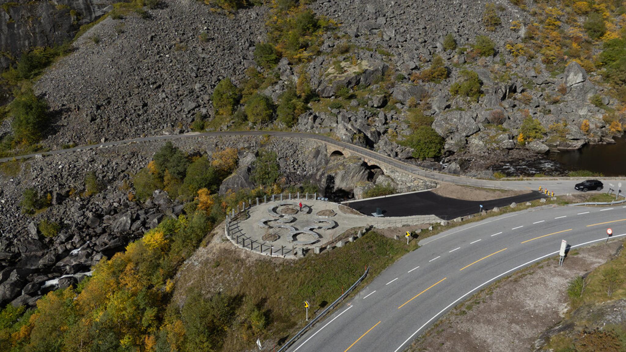 A rest stop with benches right by an old stone bridge.