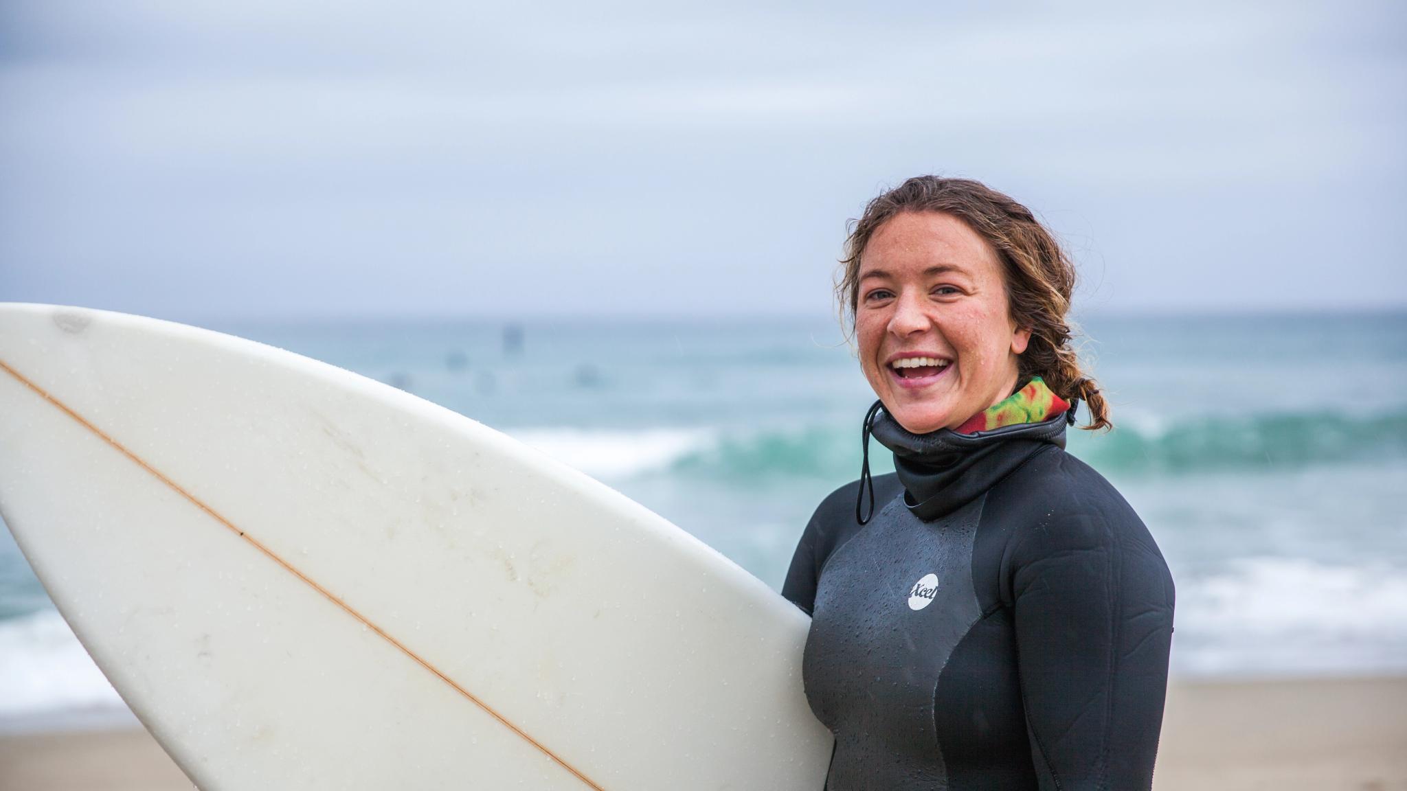 Woman holding a surf board on the Solstranden beach outside Stavanger in Fjord Norway