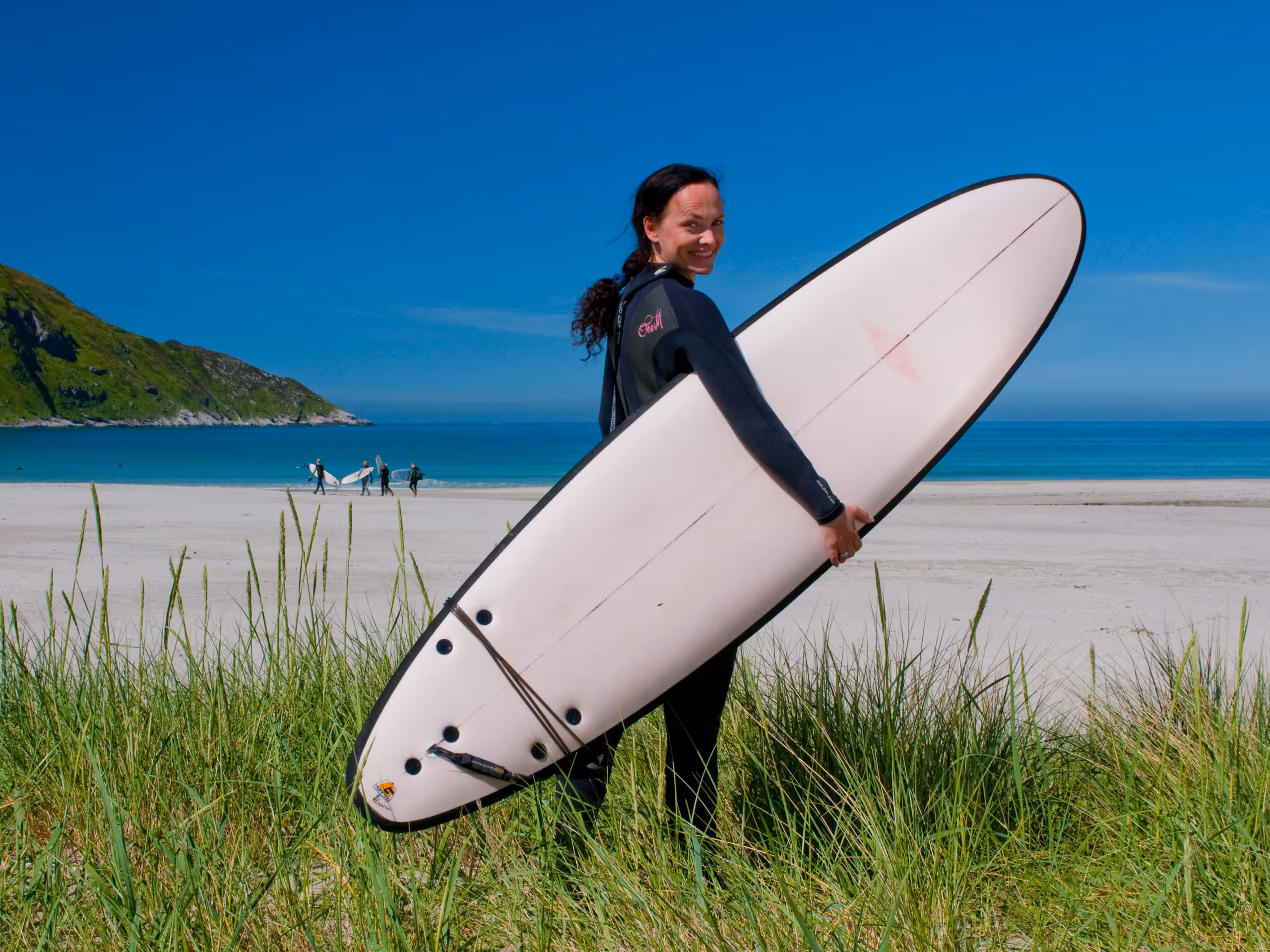 A woman with a surfboard at the beach at Hoddevik in Fjord Norway