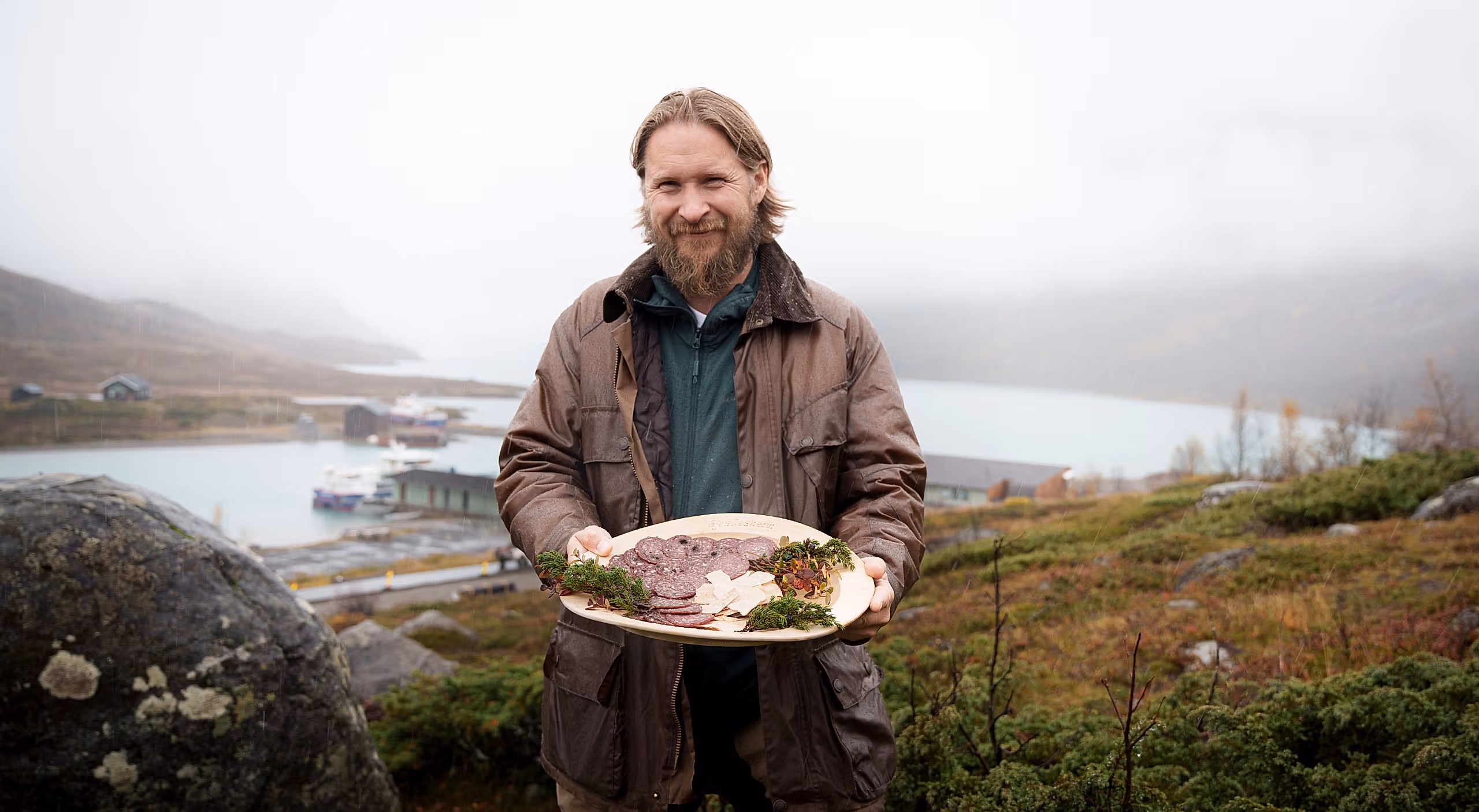 A man in nature holding a plate with local products.