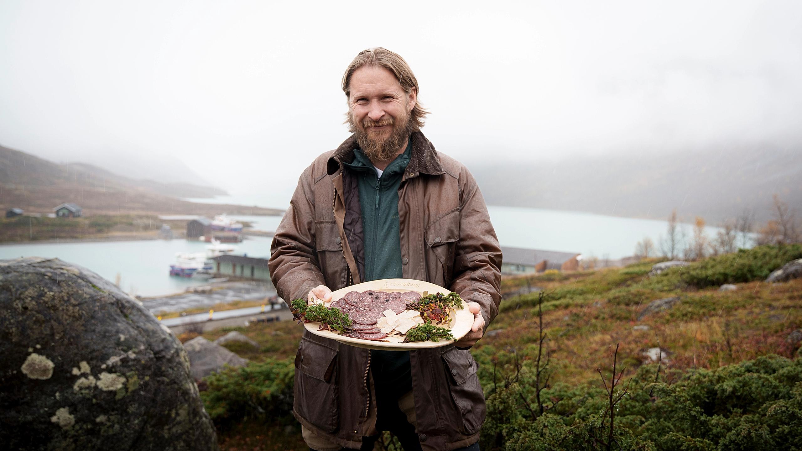 A man in nature holding a plate with local products.