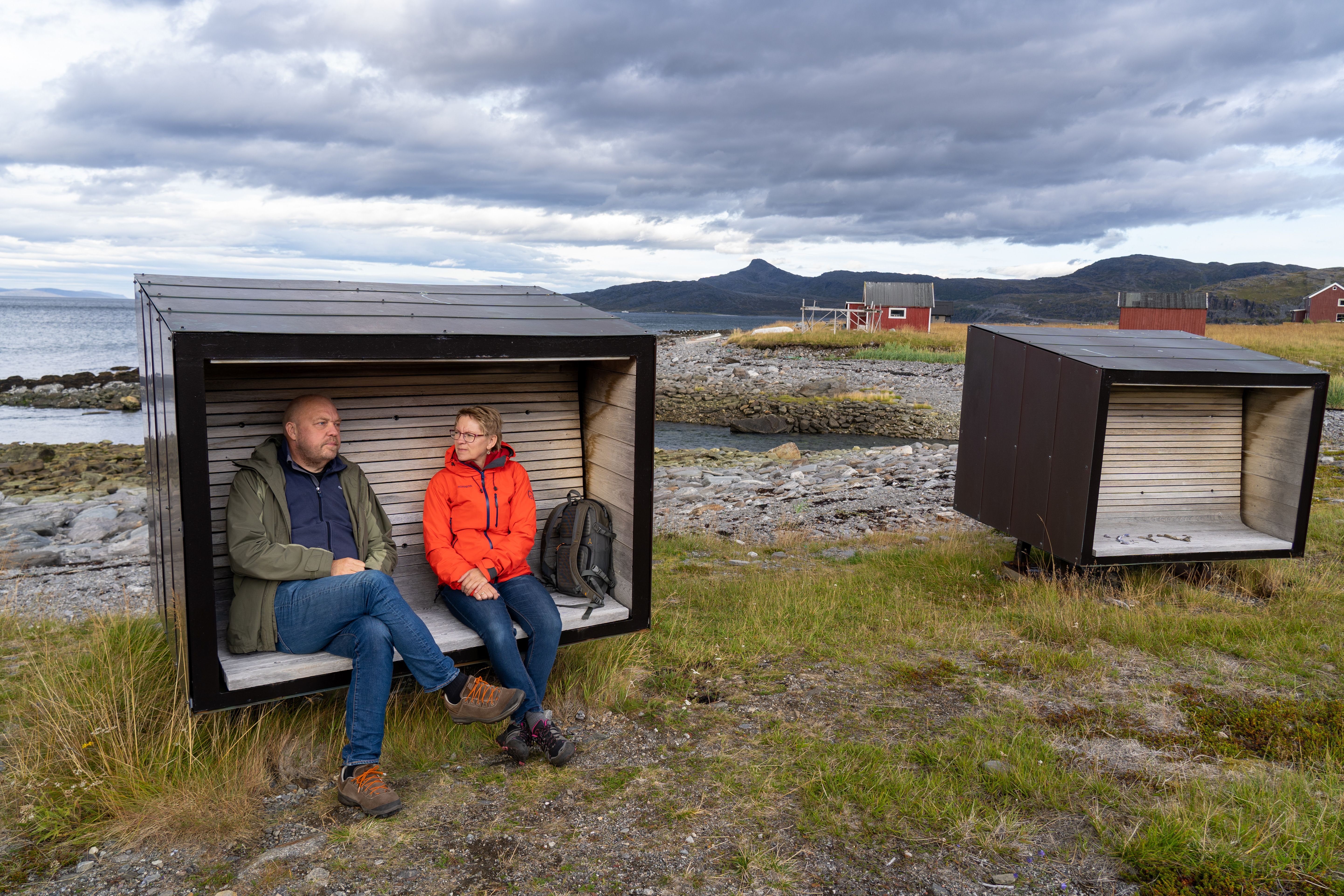 A man and a woman sit on a bench at Snefjord Rest Area